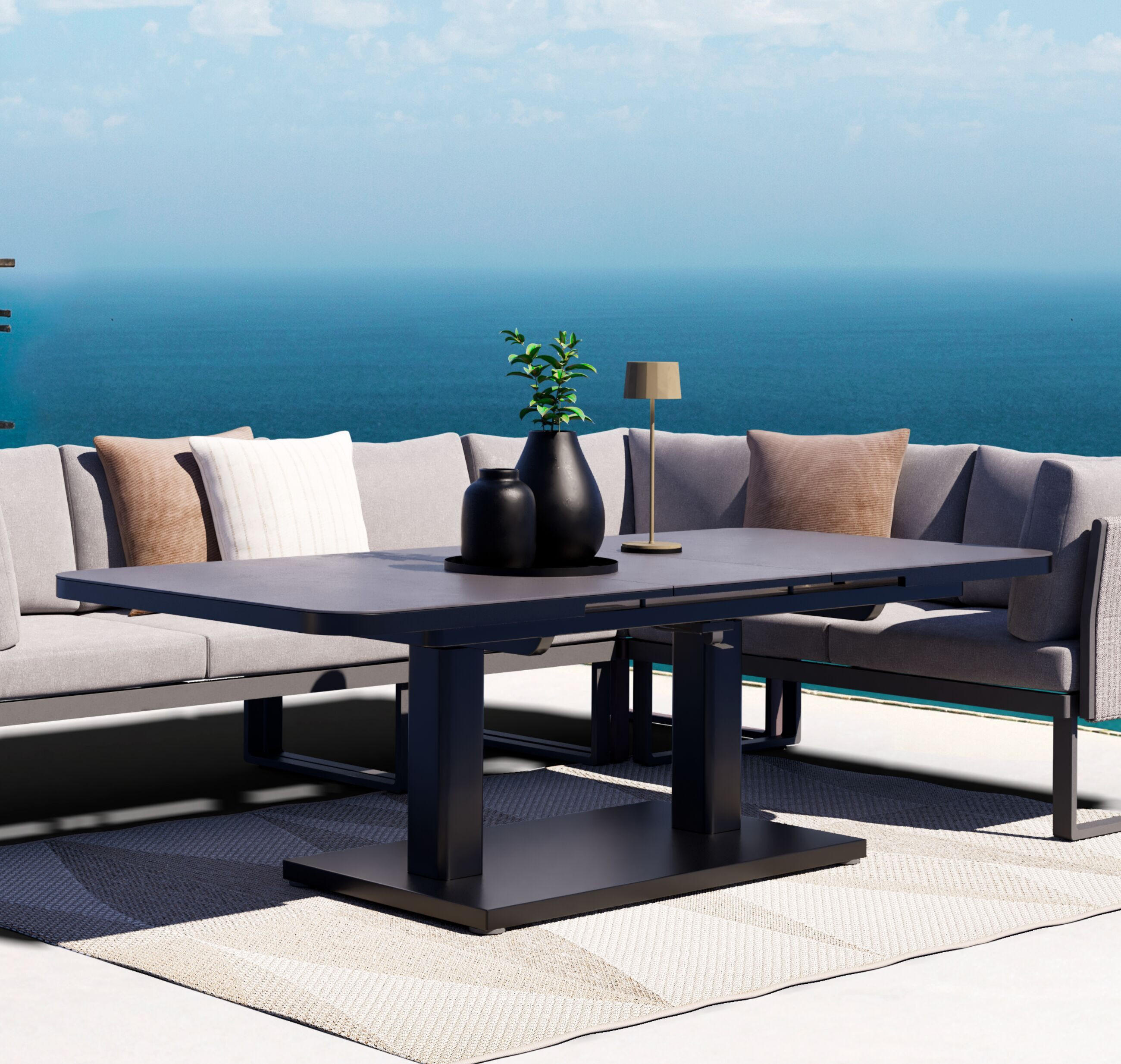 Graue Outdoor-Sitzgruppe mit Ecksofa und großem Tisch auf heller Terrasse am Pool, im Hintergrund weiter Meerblick.