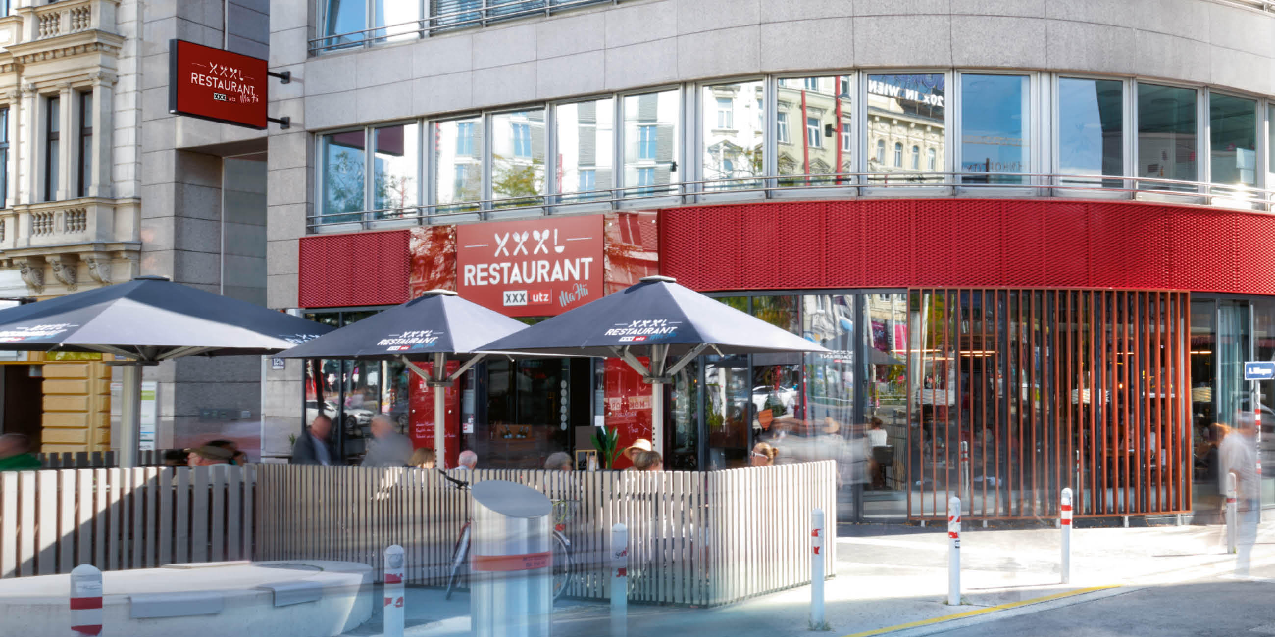 Außenansicht des XXXL Restaurant mit Terrasse und Sonnenschirmen