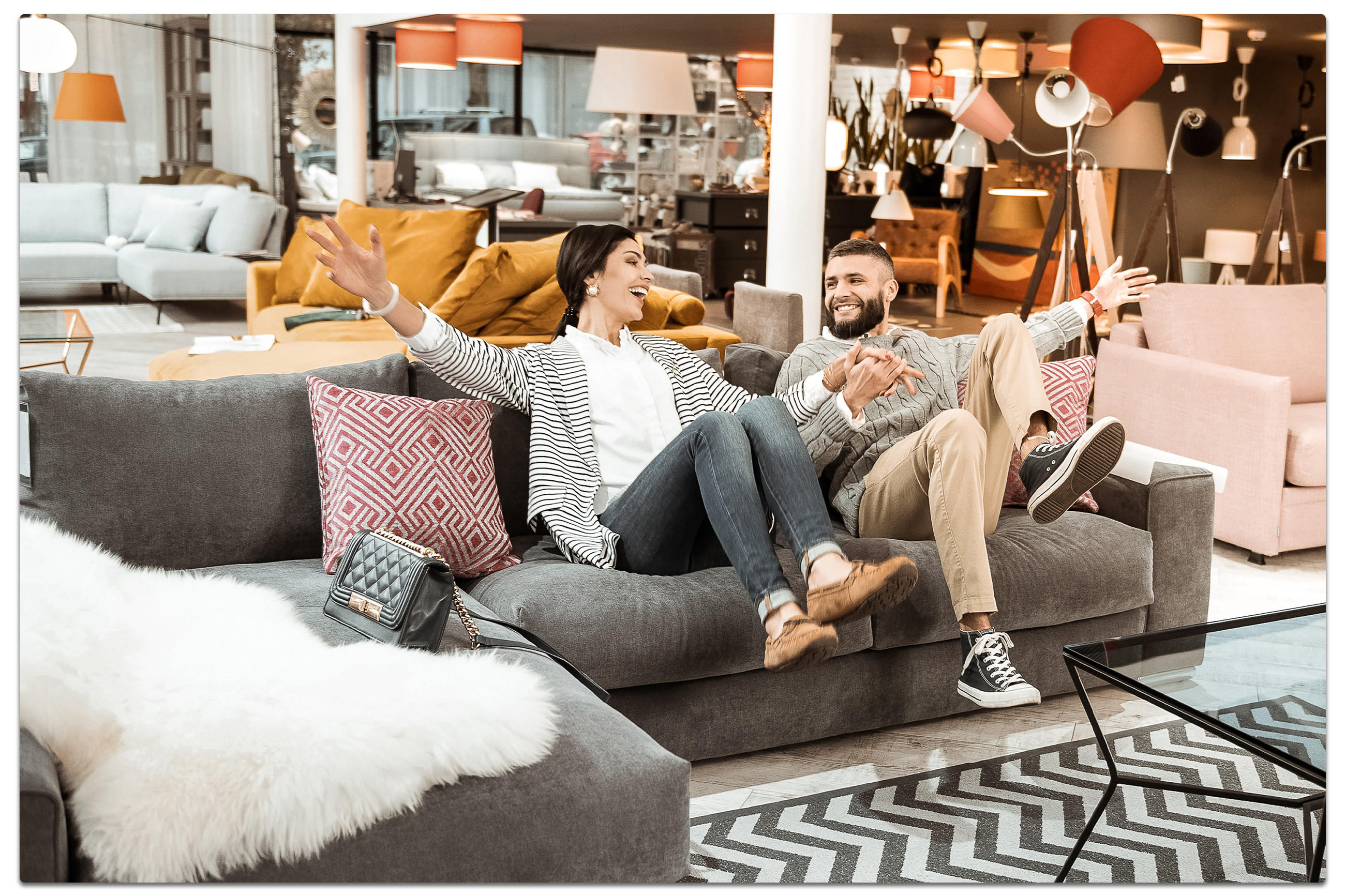 Ein Paar sitzt auf einer Couch in einem Möbelgeschäft und betrachtet die Einrichtungsmöglichkeiten.
