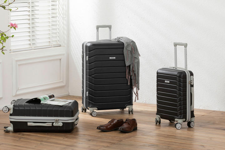 Drei Koffer auf einem Holzfußboden, ideal für Reisen mit Handgepäck.