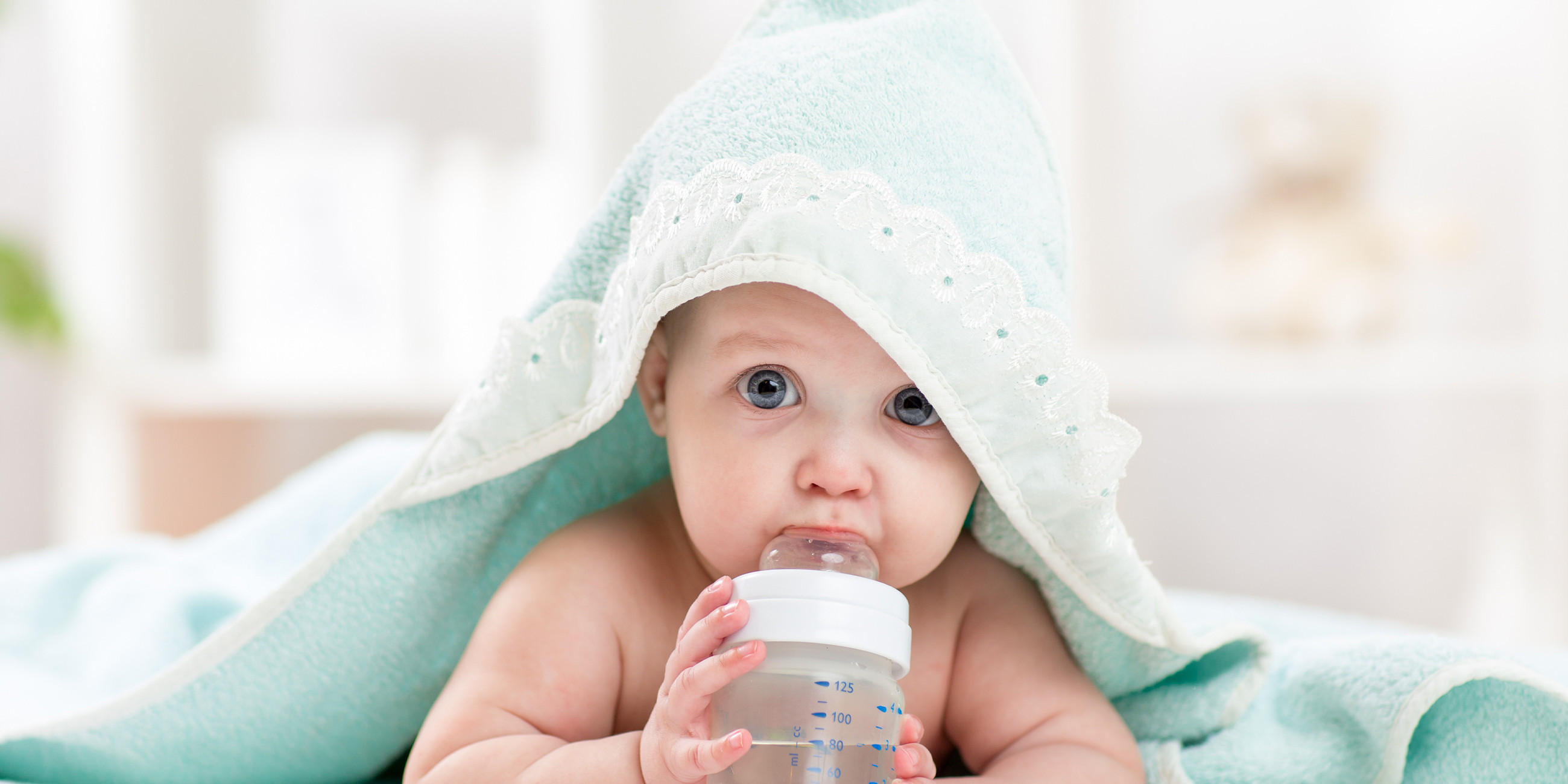 Baby in einem Handtuch mit einer Flasche in der Hand