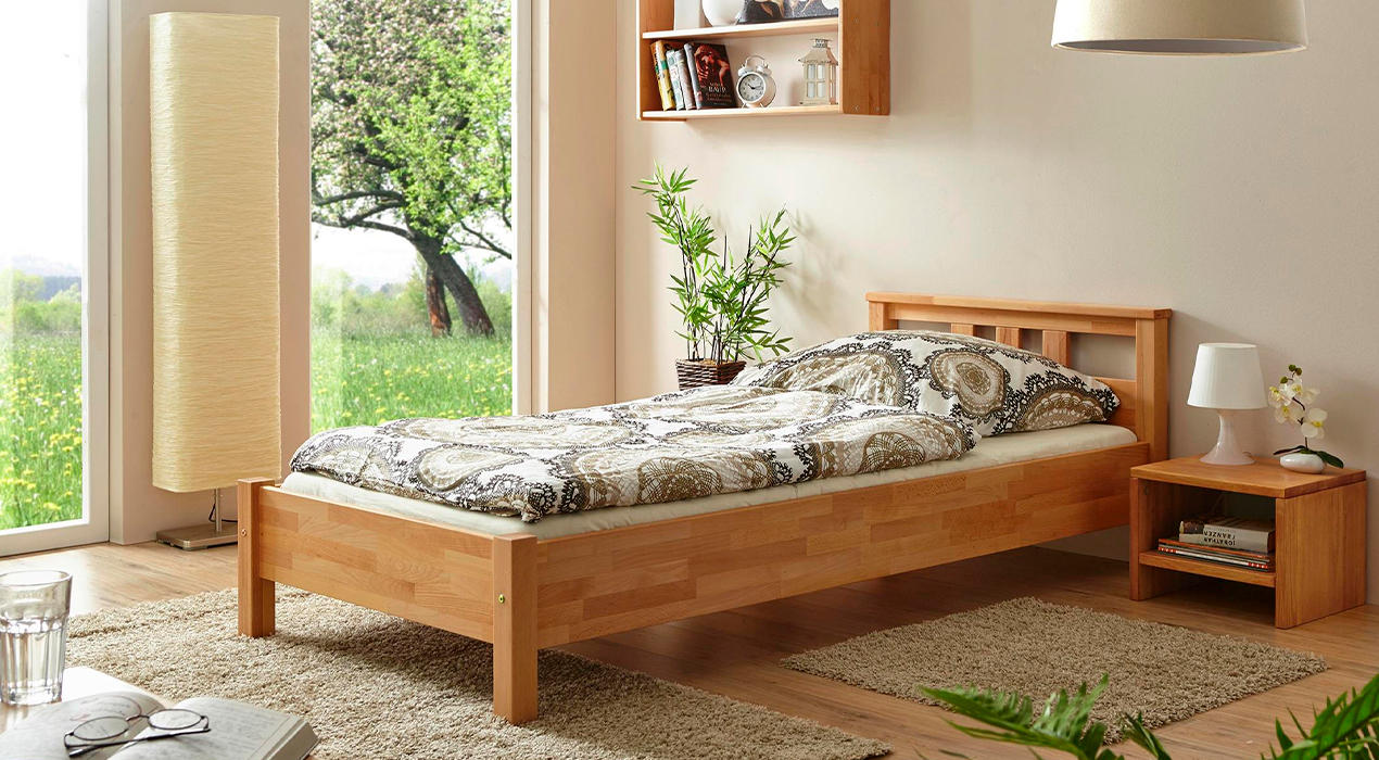 Schmales Holzbett im schlichten Design mit beiger Bettwäsche.