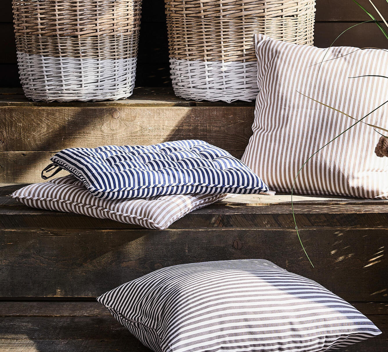 Tri črtaste blazine na leseni klopi.