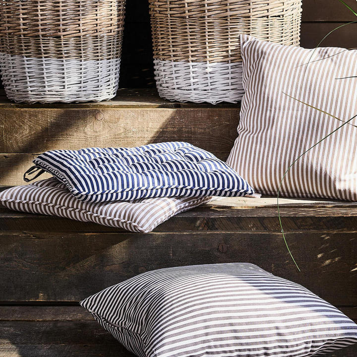 Tri črtaste blazine na leseni klopi.