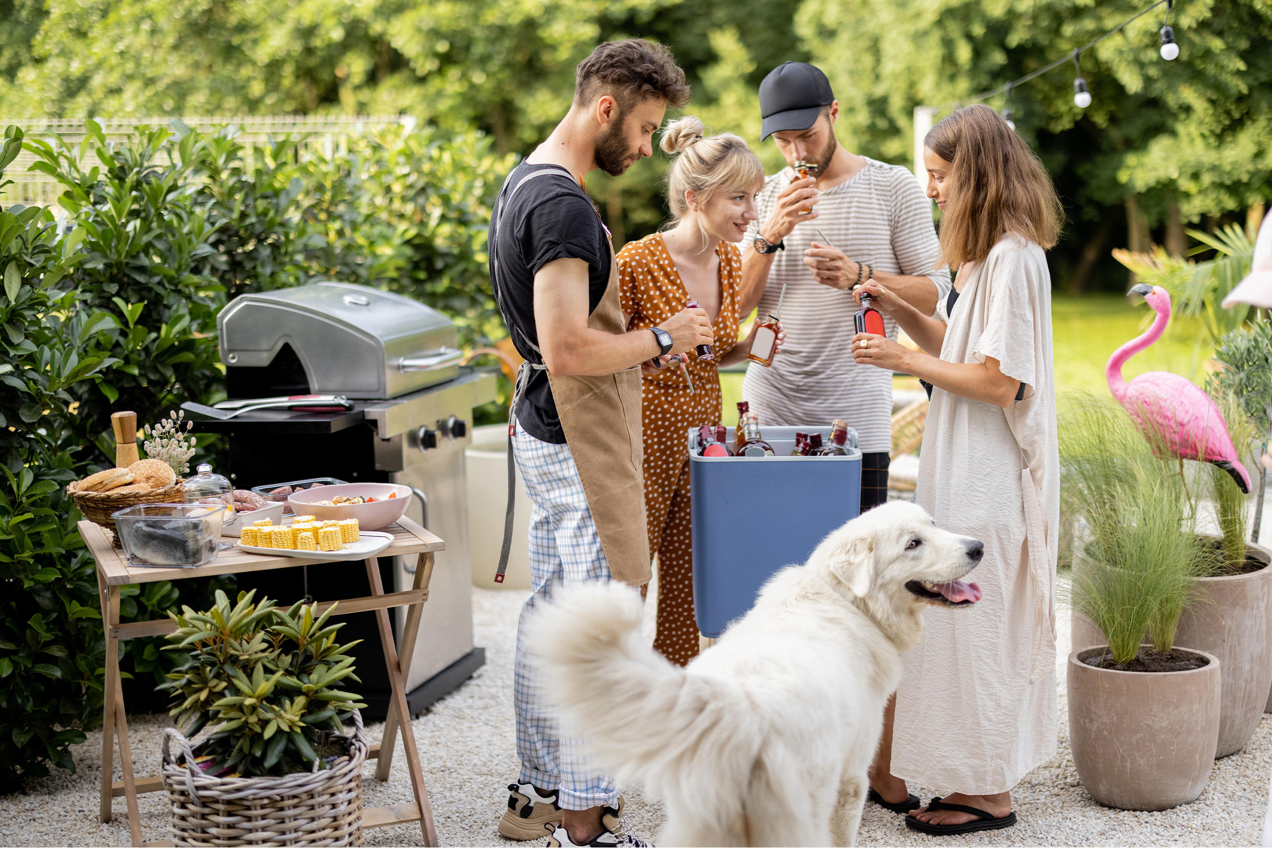 Leute stehen um einen Grill herum, während ein Hund in der Nähe steht