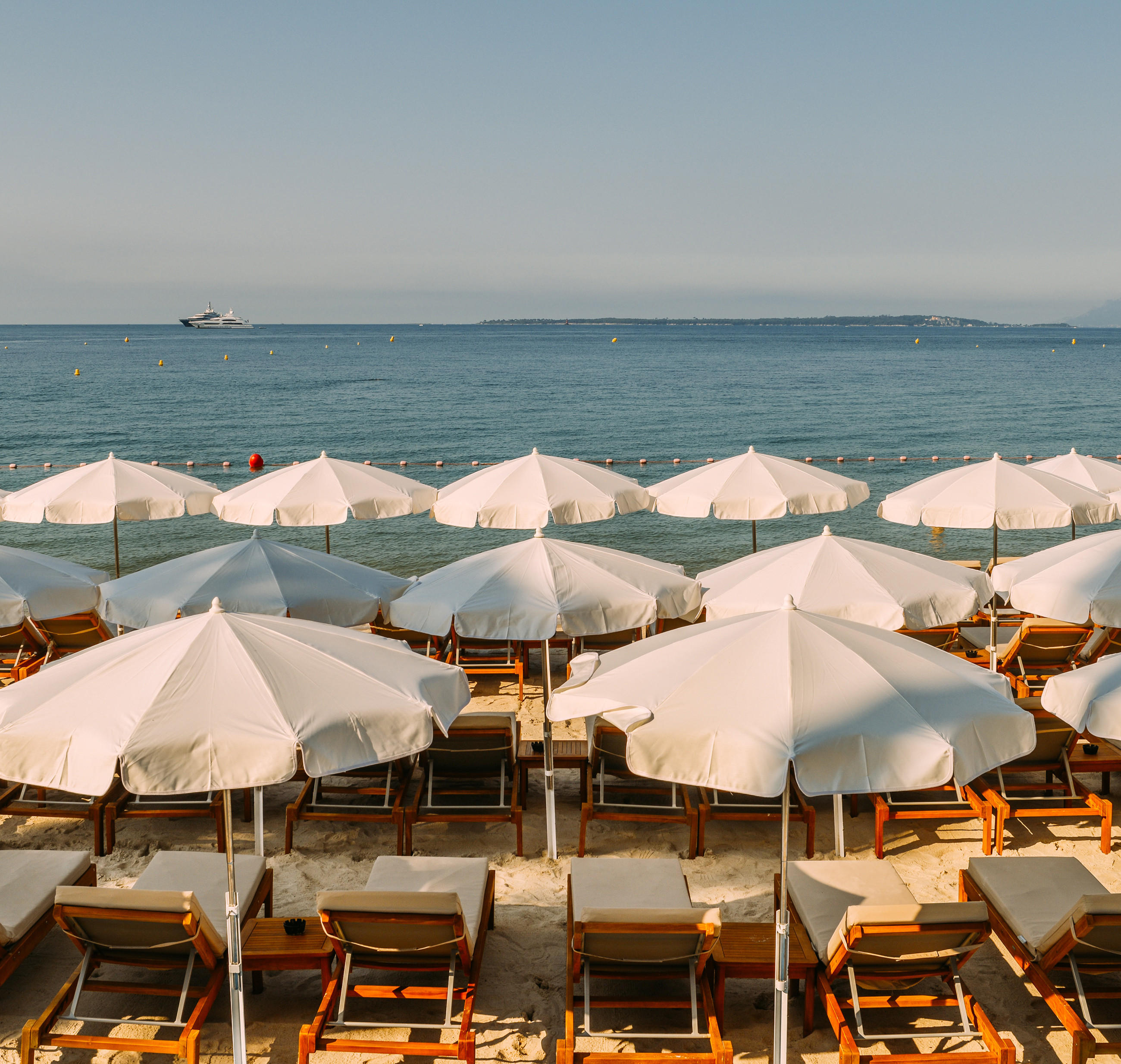 Strand mit weißen Sonnenschirmen und Liegen an der Französischen Riviera.