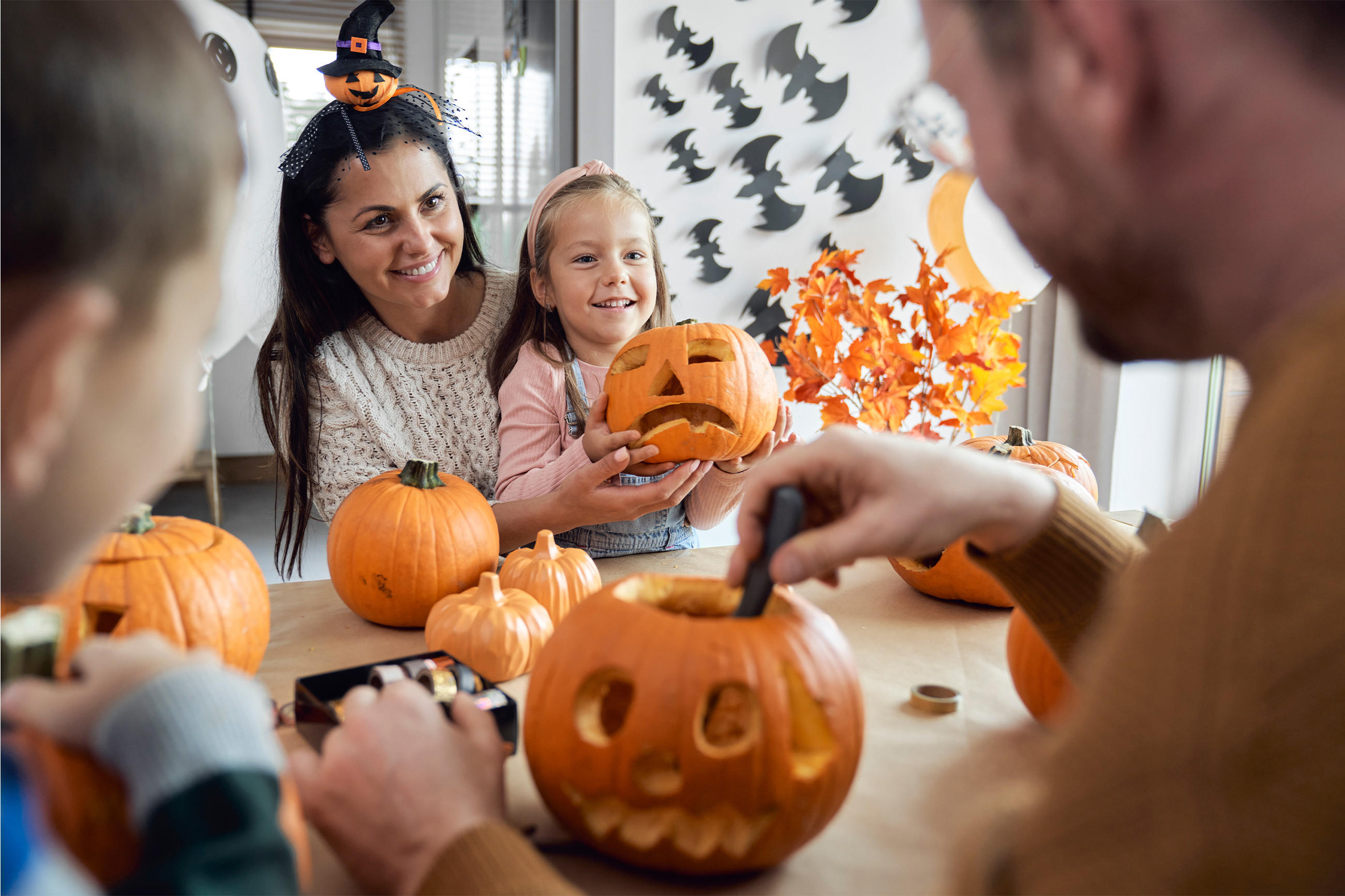 Familienmitglieder schnitzen Kürbisse zusammen, um sich auf Halloween vorzubereiten.