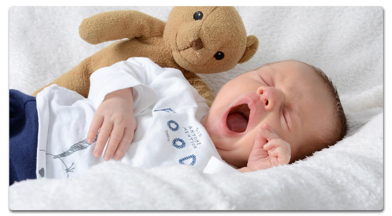 gähnendes baby mit Kuscheltier