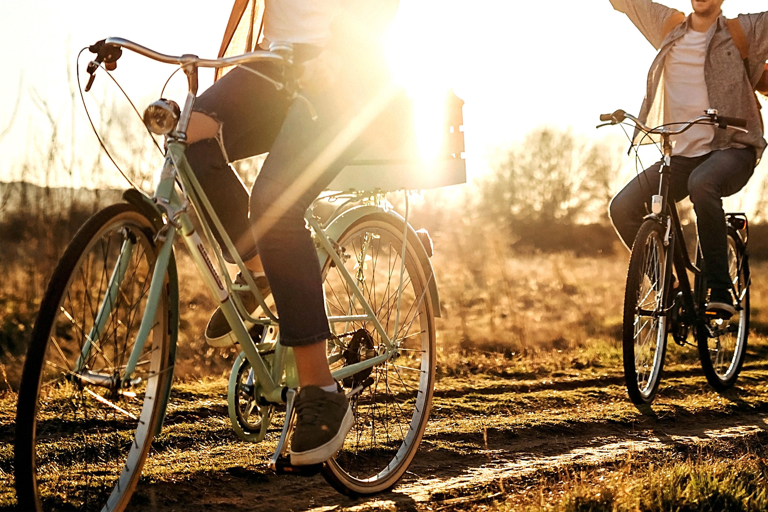 Zwei Personen auf Fahrrädern unterschiedlicher Rahmengröße fahren einen Schotterweg entlang.