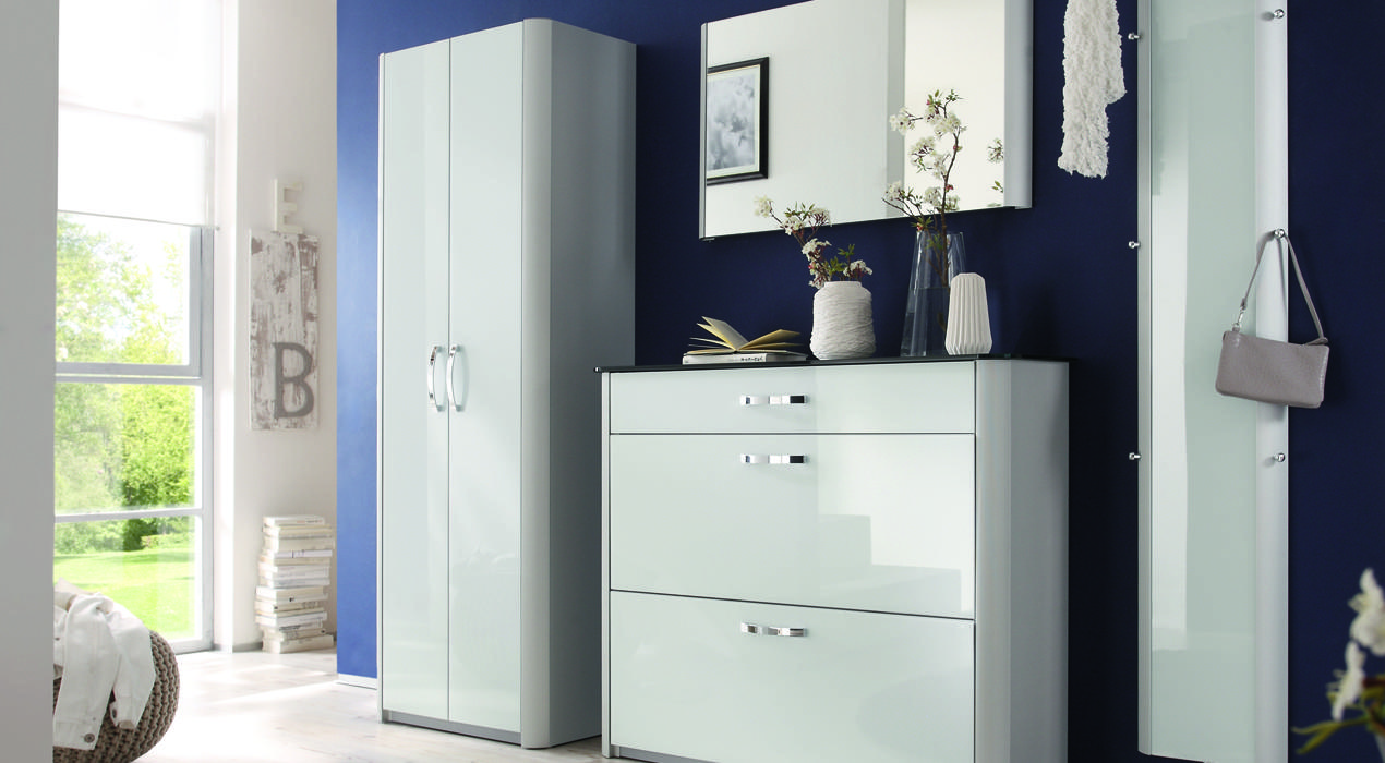 Moderner Flur mit Möbeln der „Garderobenserie Milano“, bestehend aus Schrank, Kommode, Spiegel und Deko vor dunkelblauer Wand