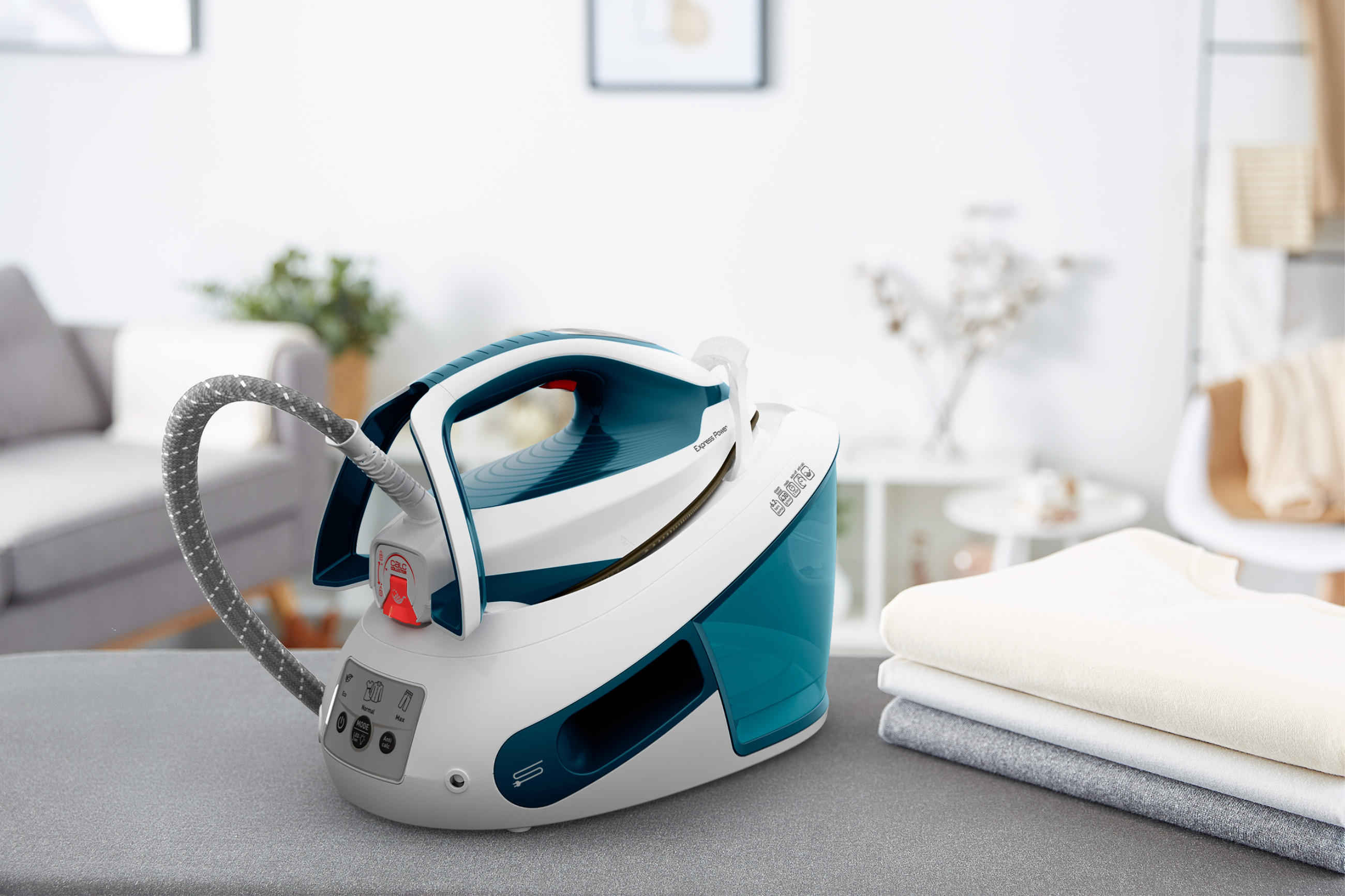 Die Express Power SV8111 Dampfbügelstation von TEFAL neben frisch gebügelter Wäsche.