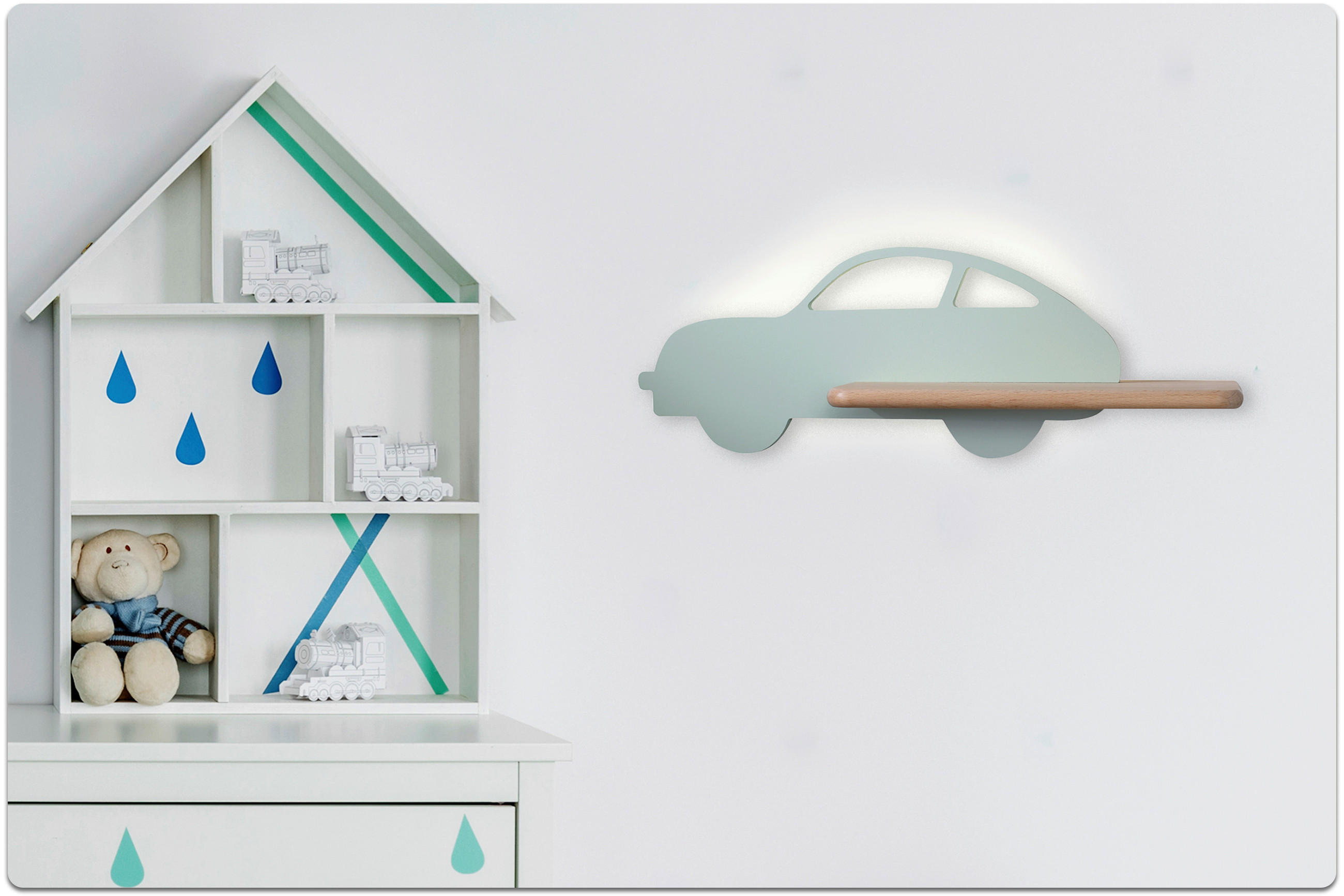 Wandlampe in Form eines Autos mit Holzgriff leuchtet an weißer Wand neben weißem Regal in Hausform mit Spielzeugzug und Teddybär.