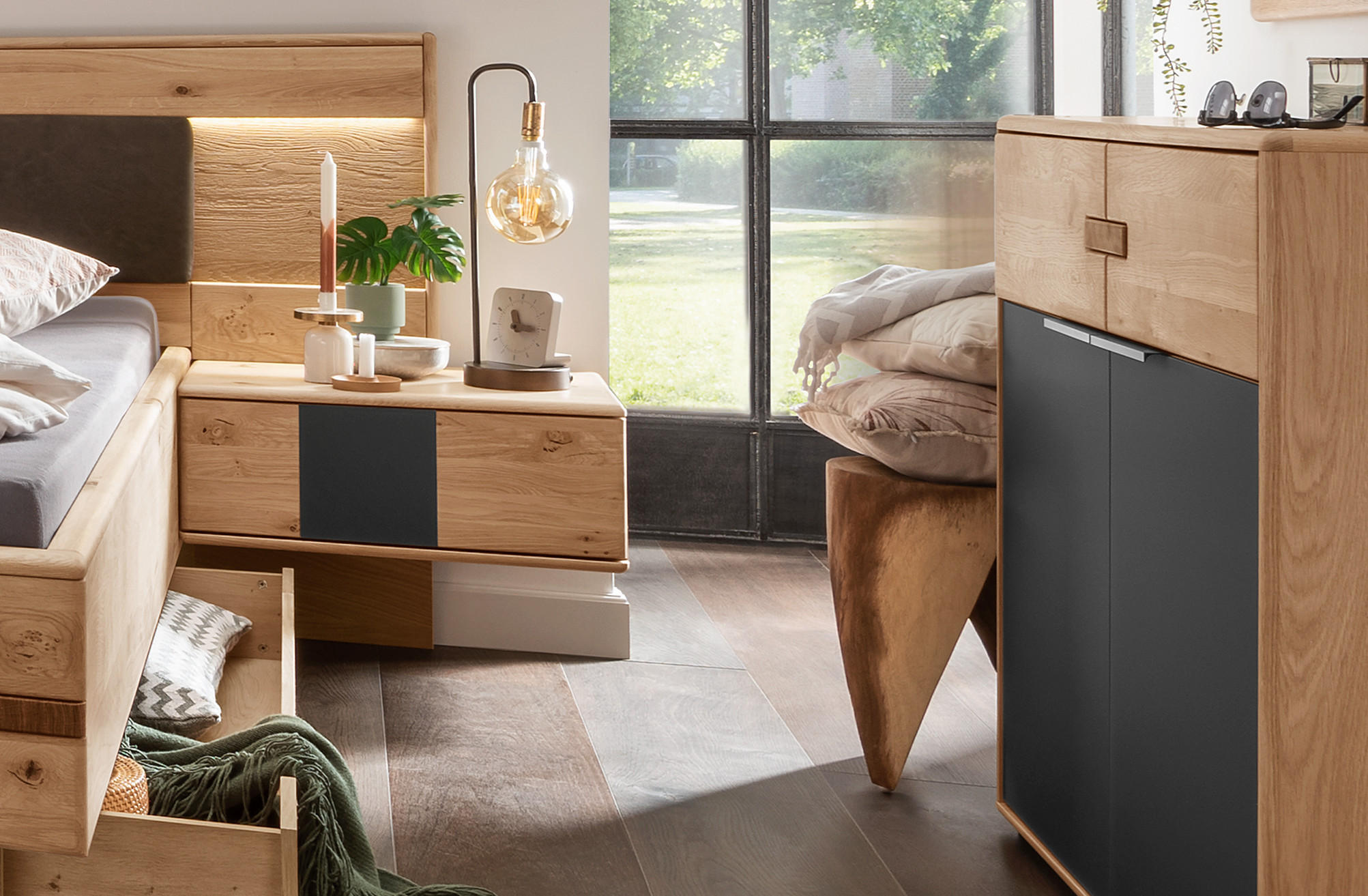 Spálňová séria Tabilo: Moderná spálňa s dreveným nábytkom - masívna dubová posteľ s LED osvetlením, nočný stolík s čiernymi detailmi, vysoká komoda s úložným priestorom a dekoratívne doplnky v škandinávskom štýle