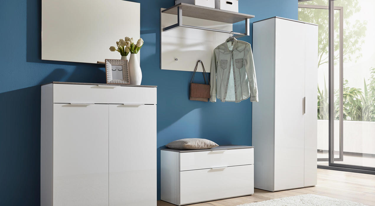 Moderner Flur mit weißen Möbeln vor blauer Wand: Spiegel, Kommode, Garderobe, Sitzbank, Schrank und Deko