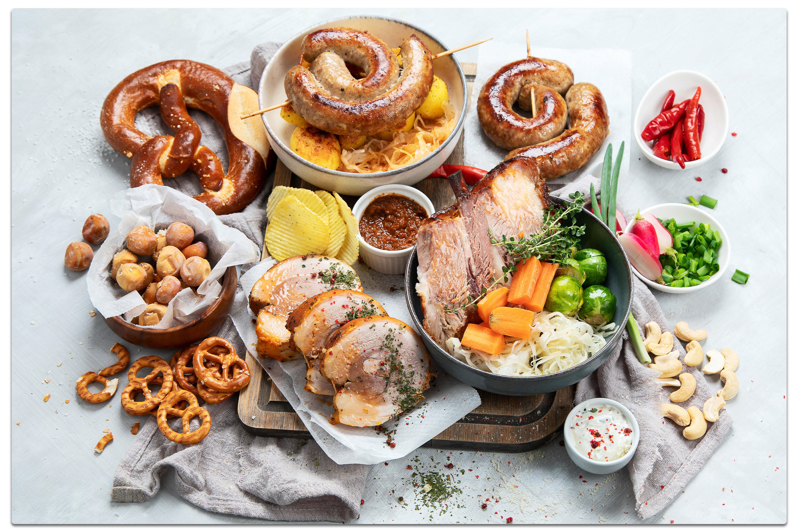 Ein Tisch mit einer Vielzahl von Speisen, die für das Oktoberfest angerichtet sind, einschließlich bayerischer Spezialitäten.