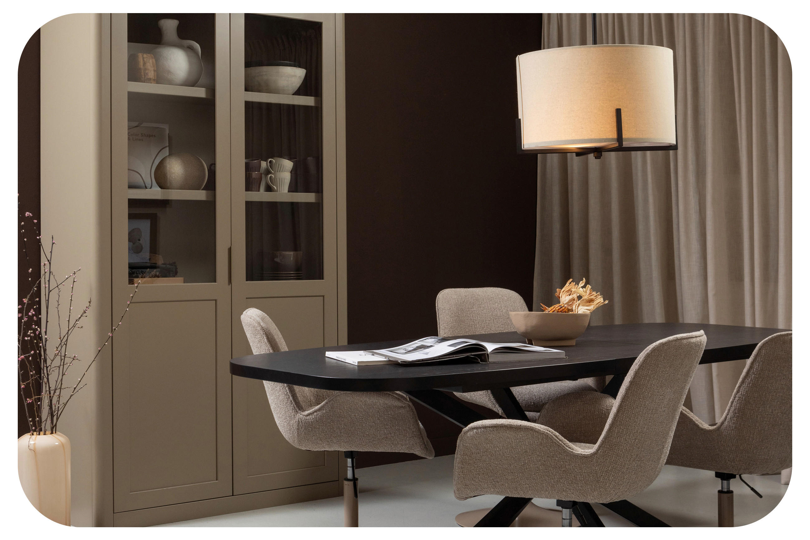 Elegantes Esszimmer mit dunklem Tisch, Polsterstühlen, Vitrine und großer Stehlampe vor Vorhängen