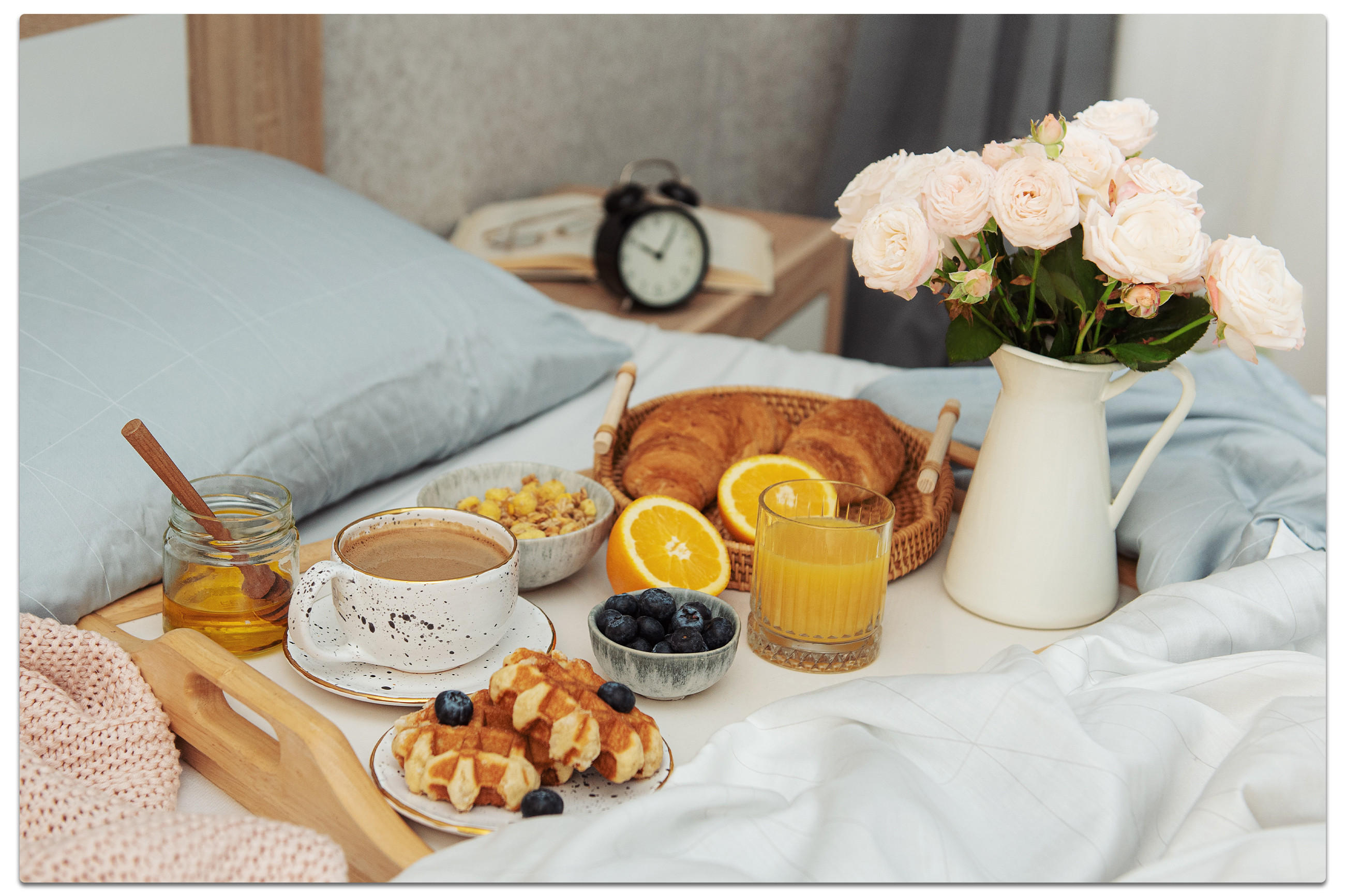 Ein Tablett mit Frühstücksartikeln auf einem Bett, das eine gemütliche Morgenstimmung vermittelt.