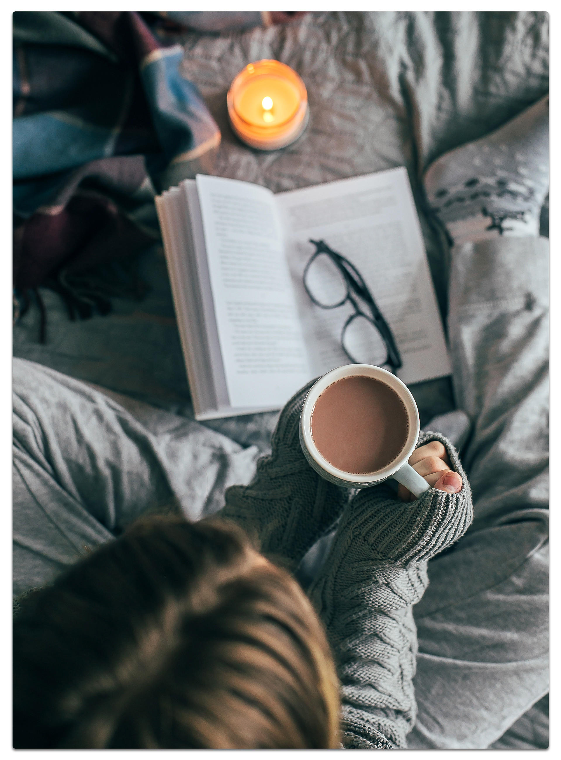 ine Frau liest ein Buch und genießt dabei eine Tasse Kaffee in einem gemütlichen Raum
