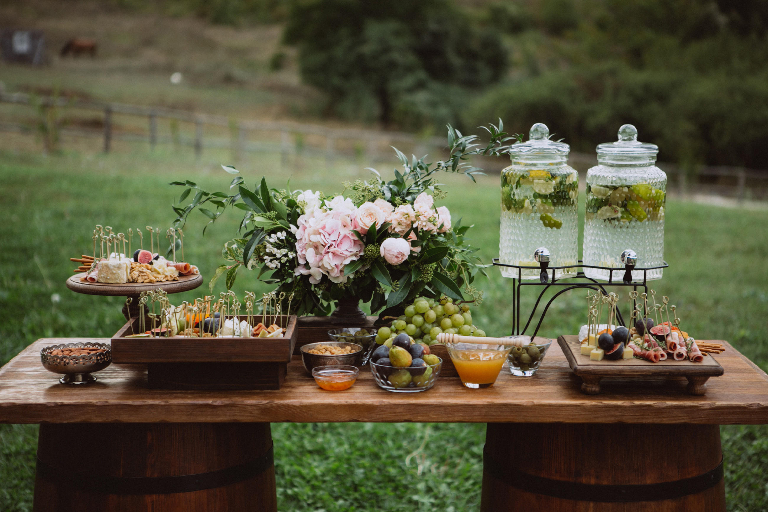 Ein rustikaler Empfangstisch für eine Gartenhochzeit, geschmückt mit Früchten und Blumen.
