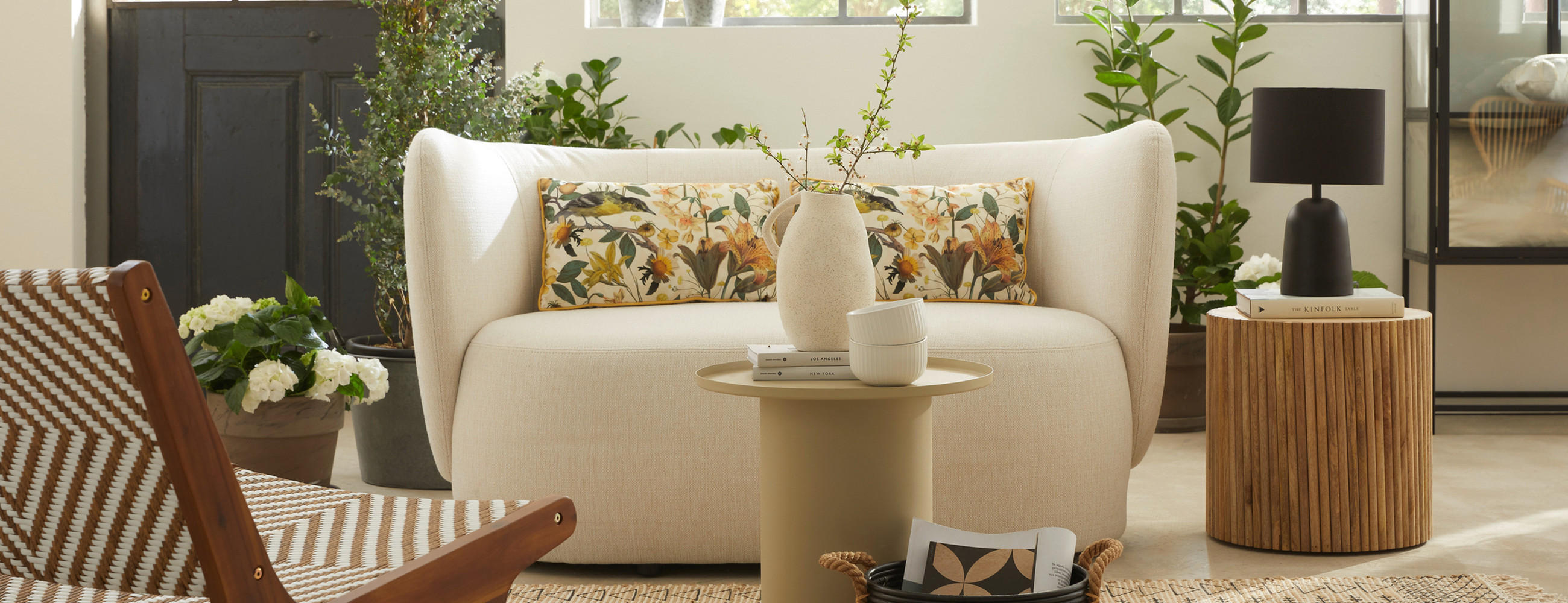 Gemütliches Wohnzimmer mit weißem Sofa und Kissen im floralen Design