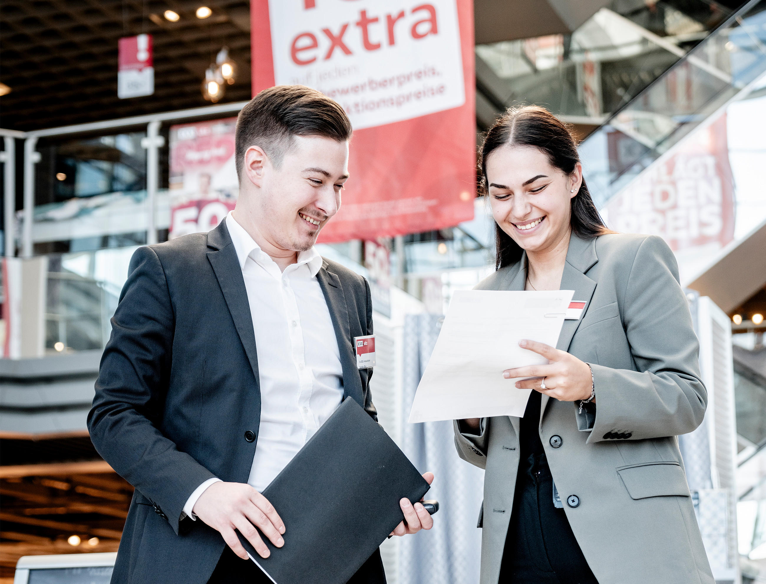 Zwei Personen in Businesskleidung stehen in einem Möbelhaus und unterhalten sich