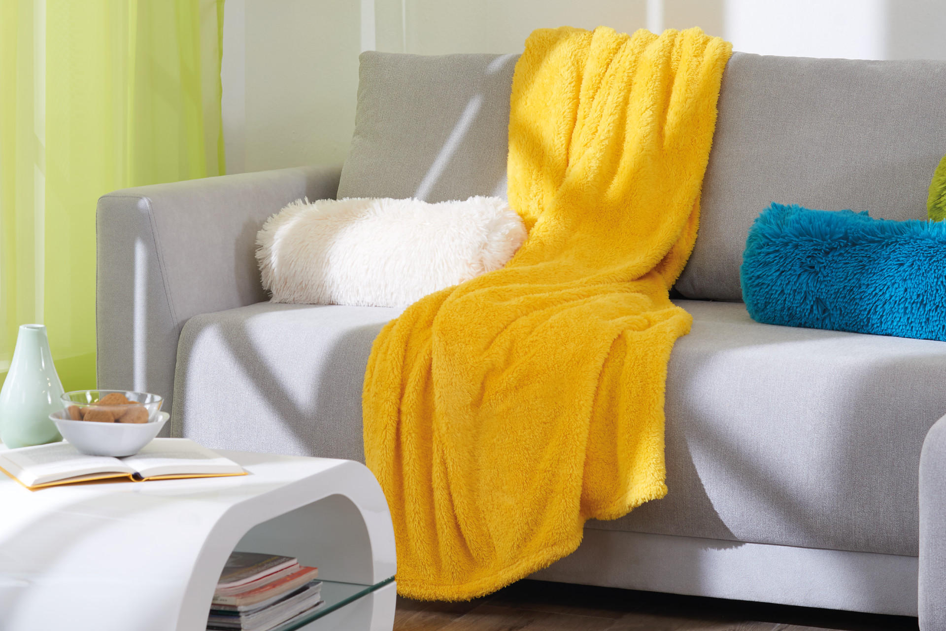 gelbe Decke und weiche Zierpolster auf der Sofa