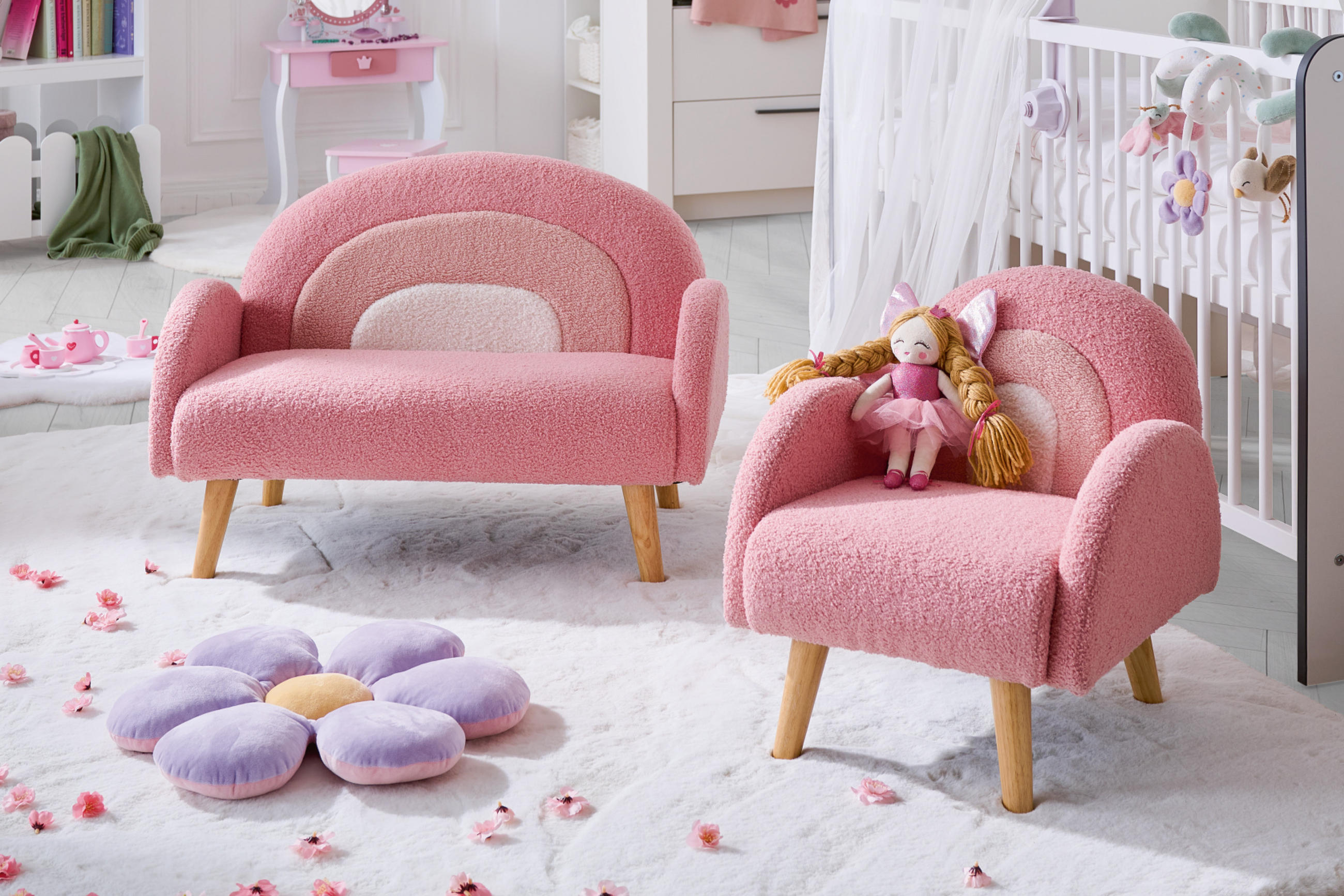 Kindersessel gepolstert in rosa und Puppe, außerdem ein lila Blumendekokissen und im Hintergrund ein weißes Gitterbett mit Seidenvorhang