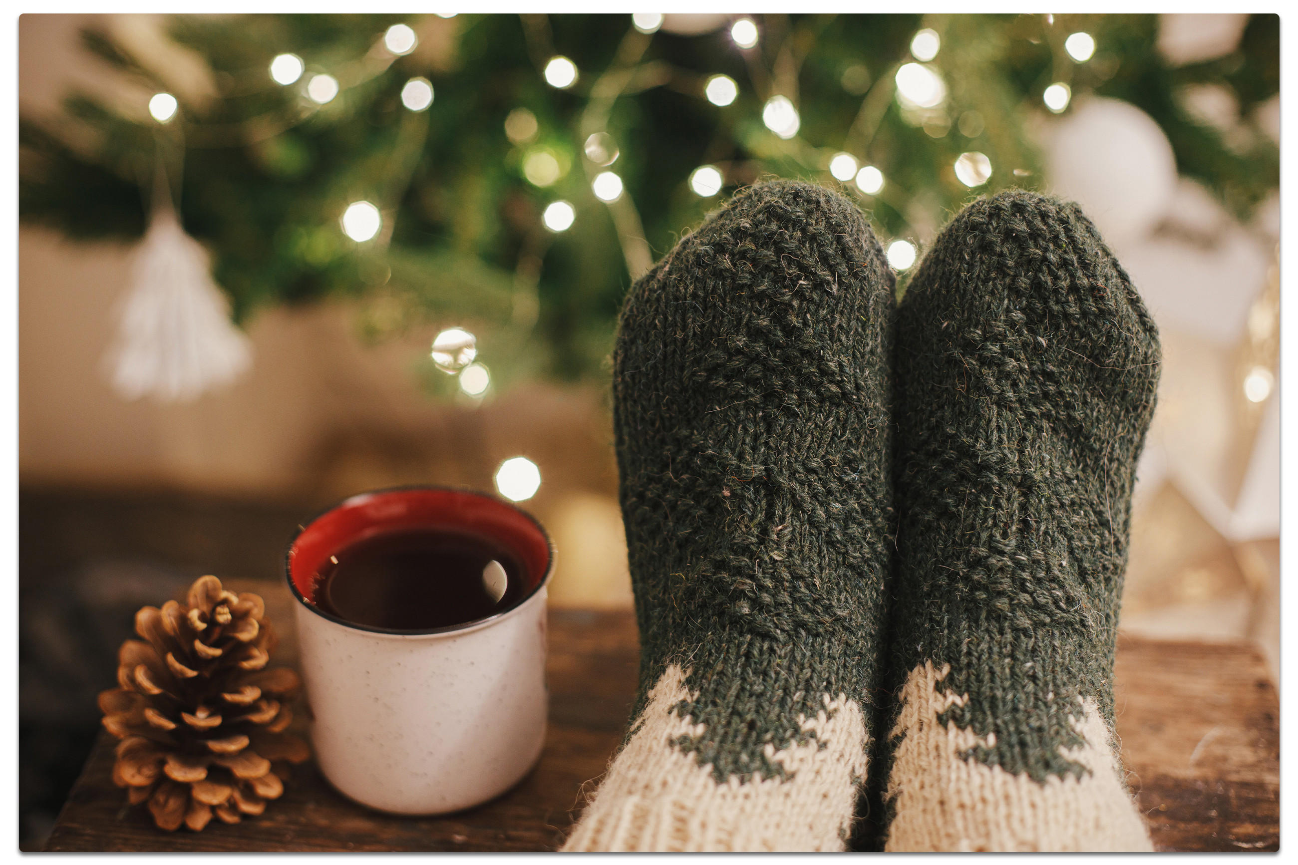 Socken, eine Tasse Kaffee und ein Weihnachtsbaum, die Gemütlichkeit und festliche Atmosphäre symbolisieren