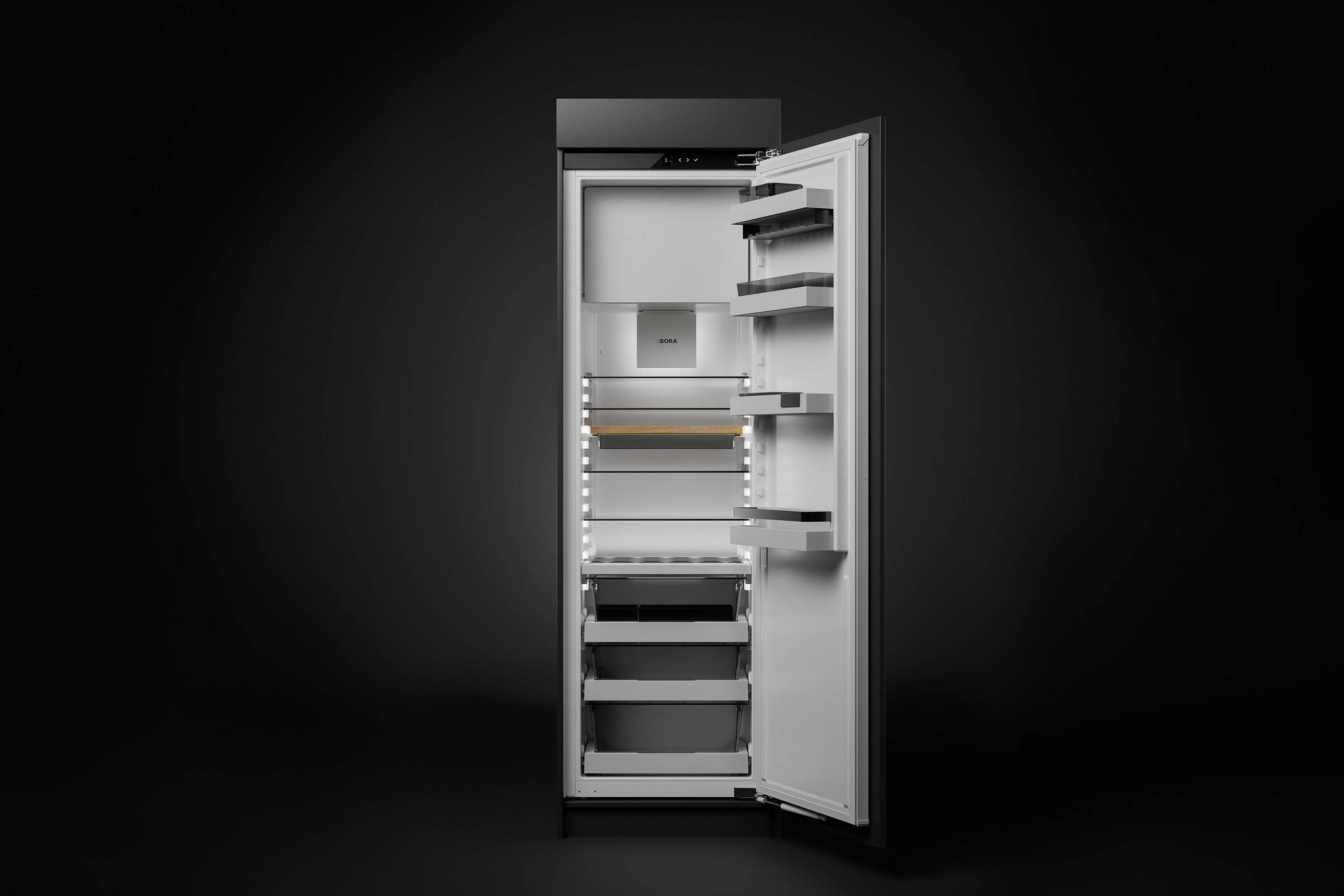Offener BORA Einbaukühlschrank vor dunklem Hintergrund mit beleuchtetem Innenraum, verstellbaren Glasablagen, Türfächern und großzügigen Auszügen im unteren Bereich.