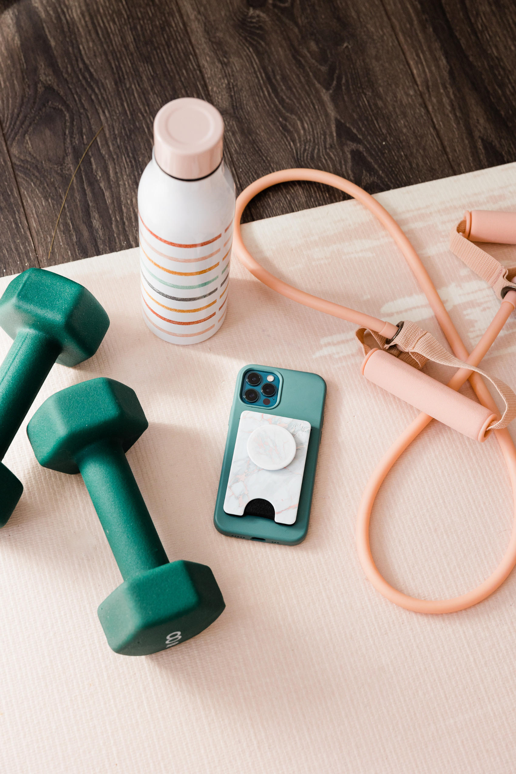 Grüner Hantel, Smartphone und weiteres Fitnesszubehör auf einem Tisch angeordnet.