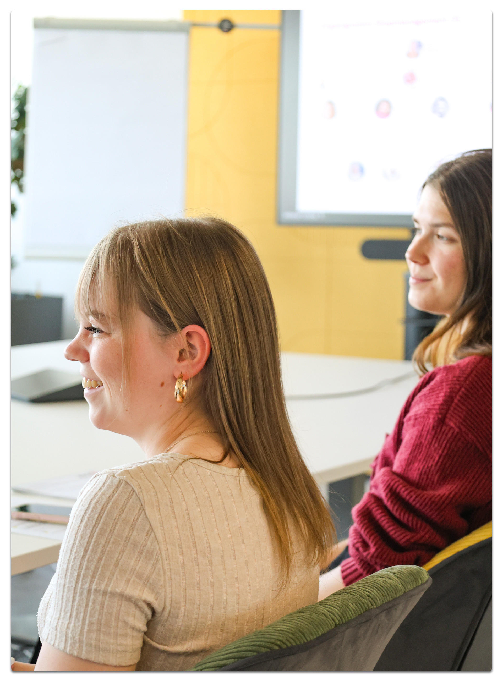 Zwei Personen in Besprechungssituation vor Whiteboard und Bildschirm.