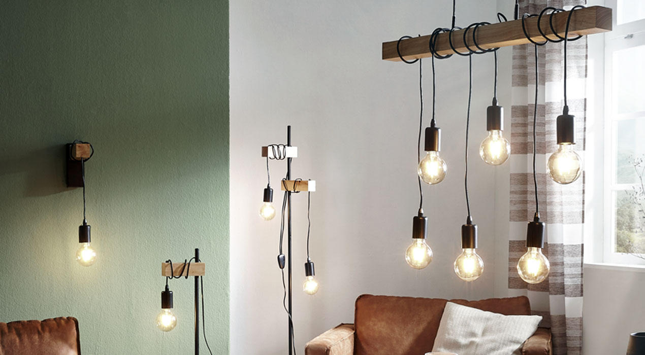 Hängelampen mit sichtbaren Glühbirnen, befestigt an rustikalen Holzbalken, verbinden industriellen Charme mit zeitgemäßem Design