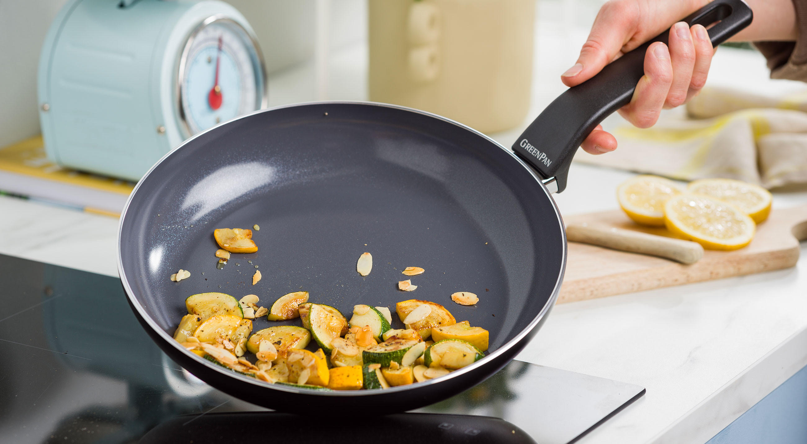 Eine Person brät Gemüse in einer Pfanne GreenPan auf dem Herd.