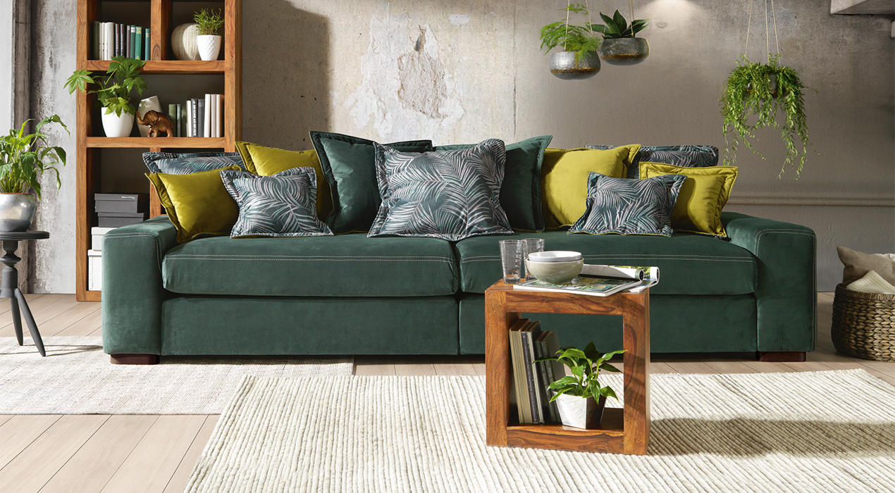Dunkelgrünes Big Sofa mit hellgrünen Kissen