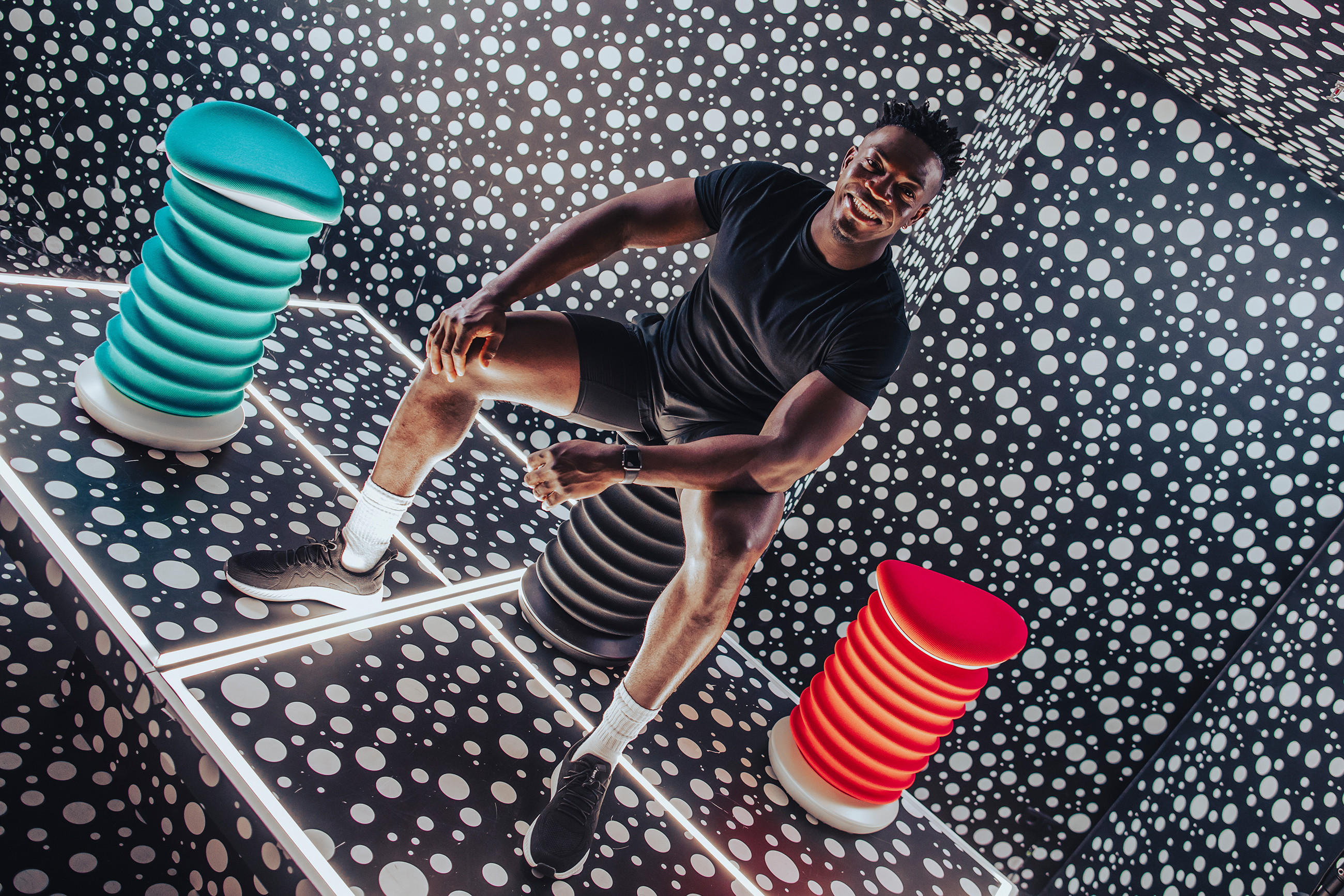 Ein Mann auf einem Stuhl in einem Raum mit vielen Punkten, der die Produktlinie SITNESS von TOPSTARS präsentiert.