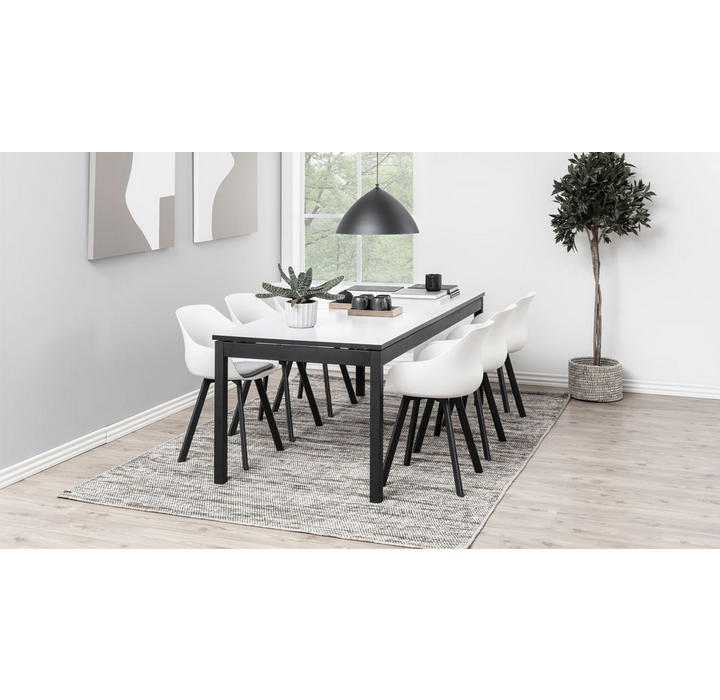 Weiße Stühle mit schwarzen Stuhlbeinen und weißer Tisch mit schwarzen Beinen