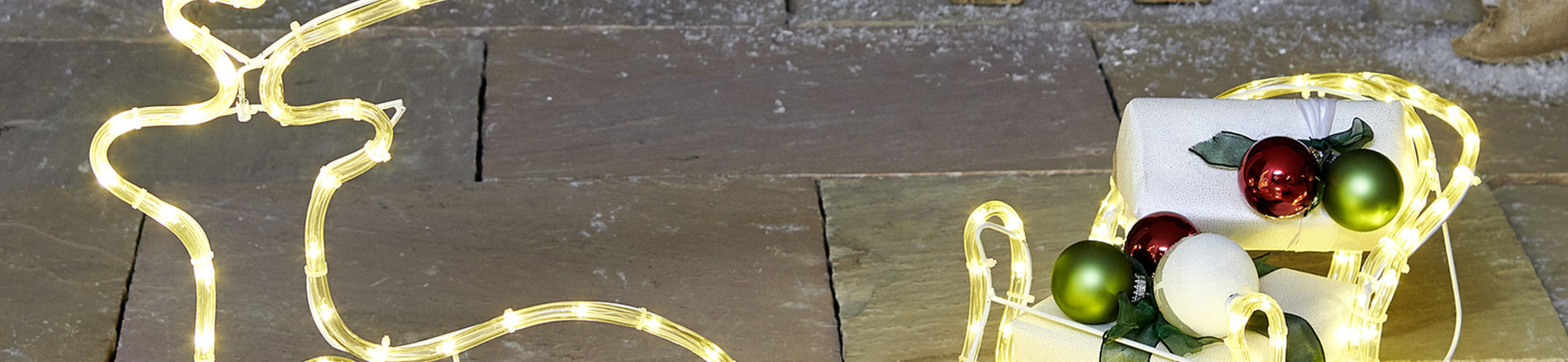 Beleuchtetes Rentier mit einem Schlitten voller Geschenke 