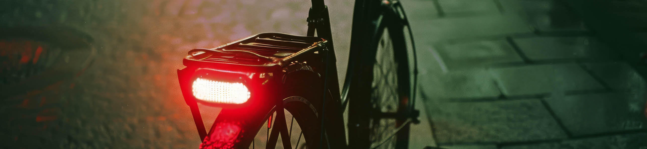 Ein Fahrrad mit einem leuchtend roten Rücklicht, bereit für die Fahrt bei Dämmerung oder Nacht.