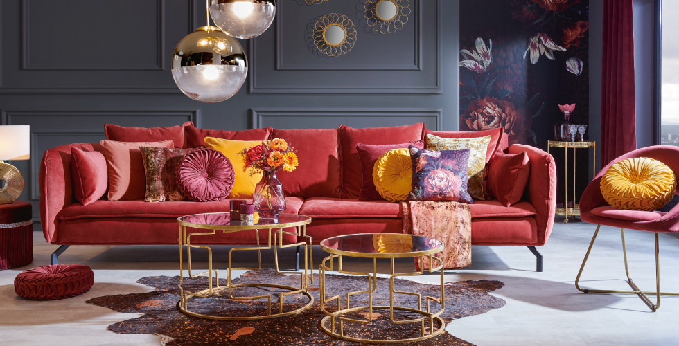 elegantes Wohnzimmer mit coralfarbener Sofa und goldenen Couchtischen