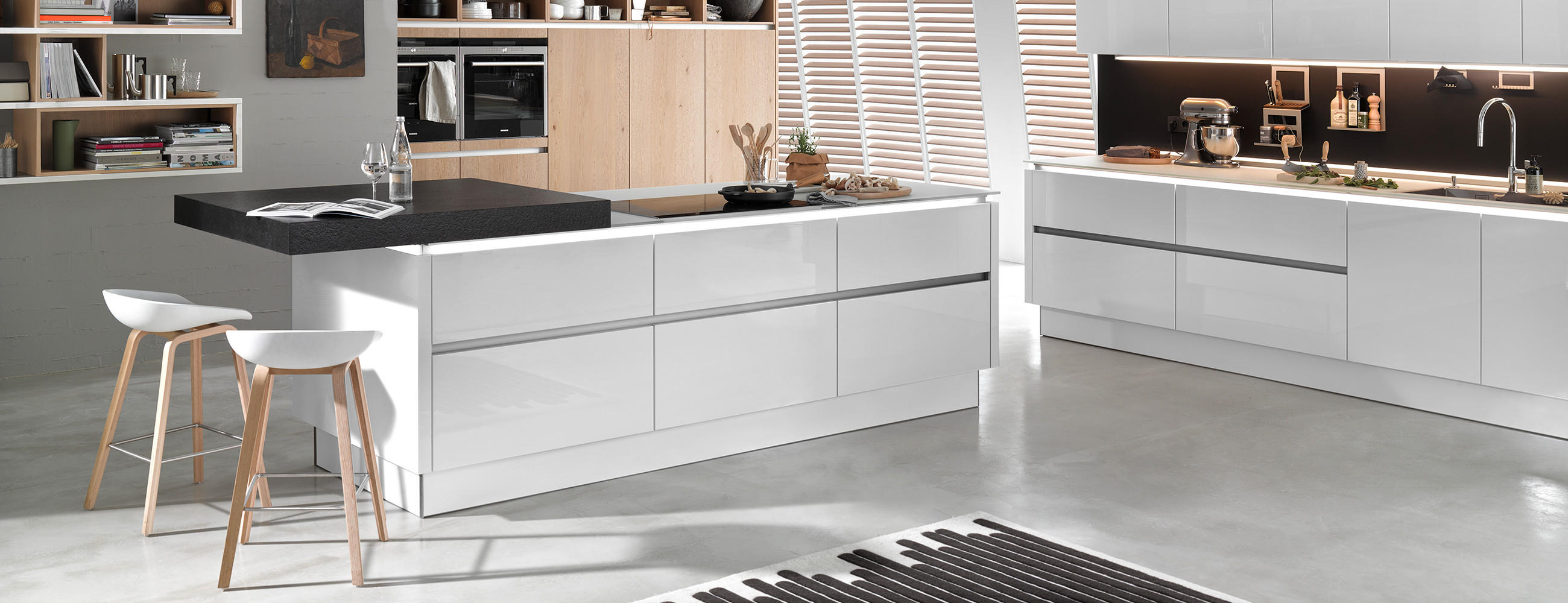 Stilvolle Küche mit Kochinsel mit modernen, grifflossen Fronten in weiß.