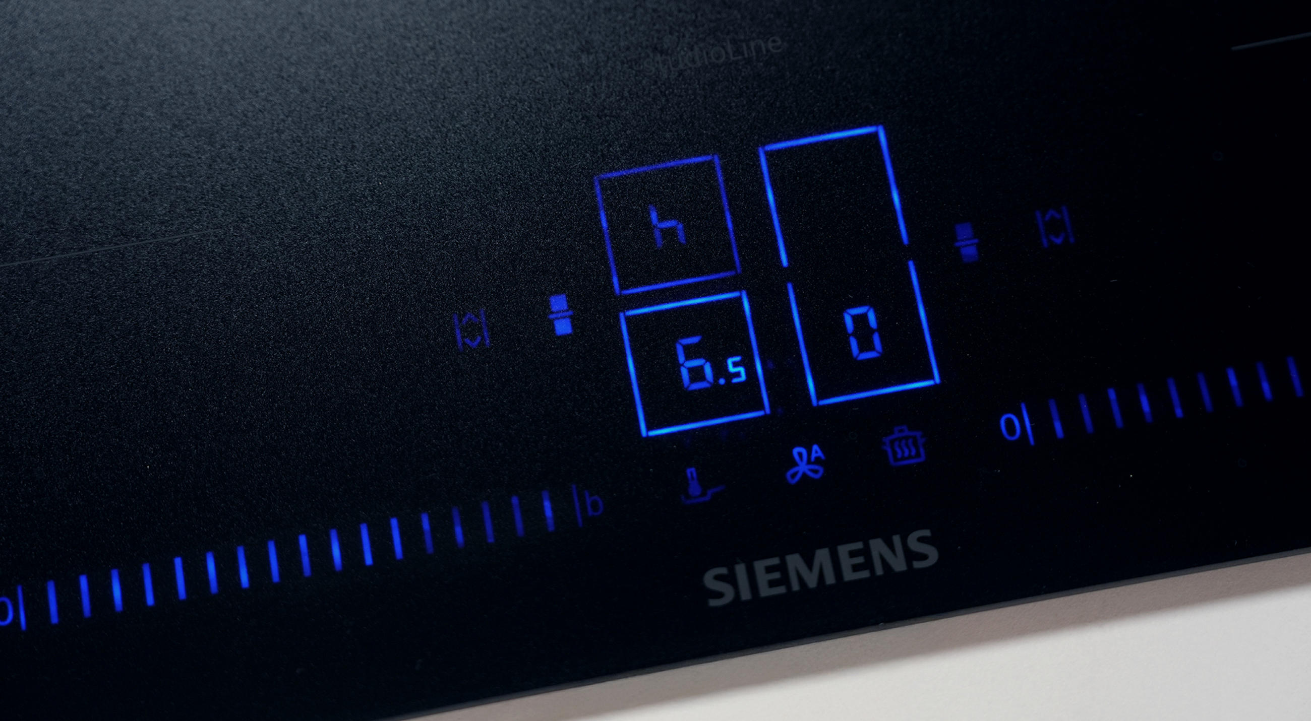 Nahaufnahme eines Siemens-Bedienfelds mit digitaler Anzeige in Blau, die Zahlen „6.5“ und „0“ sowie verschiedene Symbole 