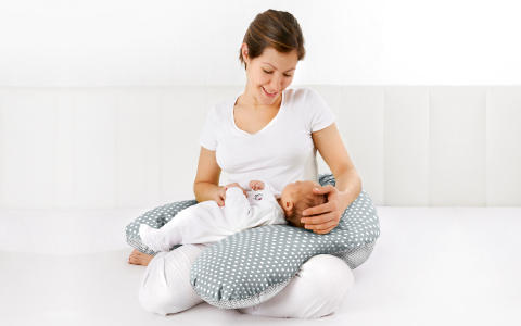 Mutter mit Baby auf Stillkissen