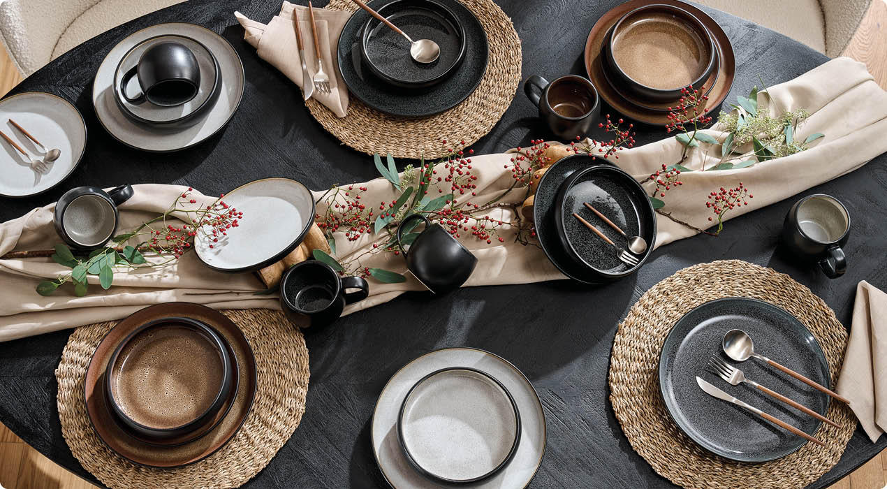 Esstisch mit gedeckten Tellern, Gläsern mit Orangensaft, Eiern in Eierbechern, Besteck und dekorativen Stoffläufern in warmen Farbtönen