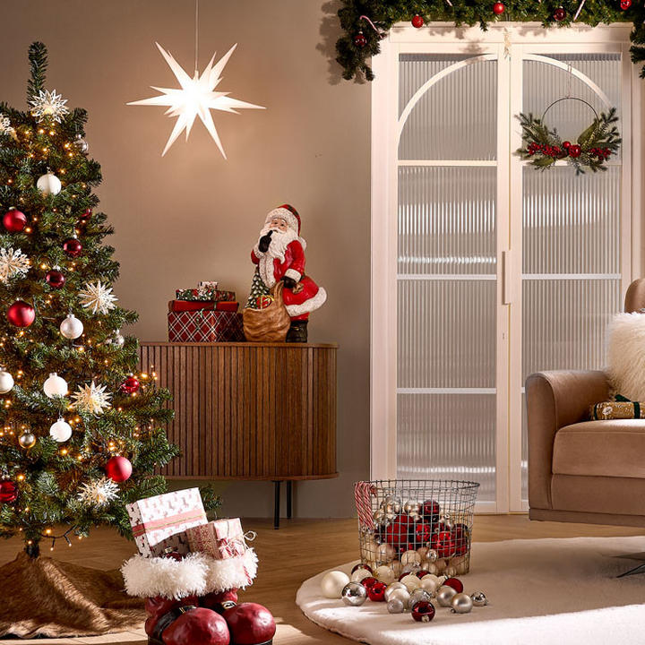 Festliche Wohnzimmer-Szene mit geschmücktem Weihnachtsbaum, Geschenken, Holzschrank mit Weihnachtsdeko und beleuchtetem Stern.