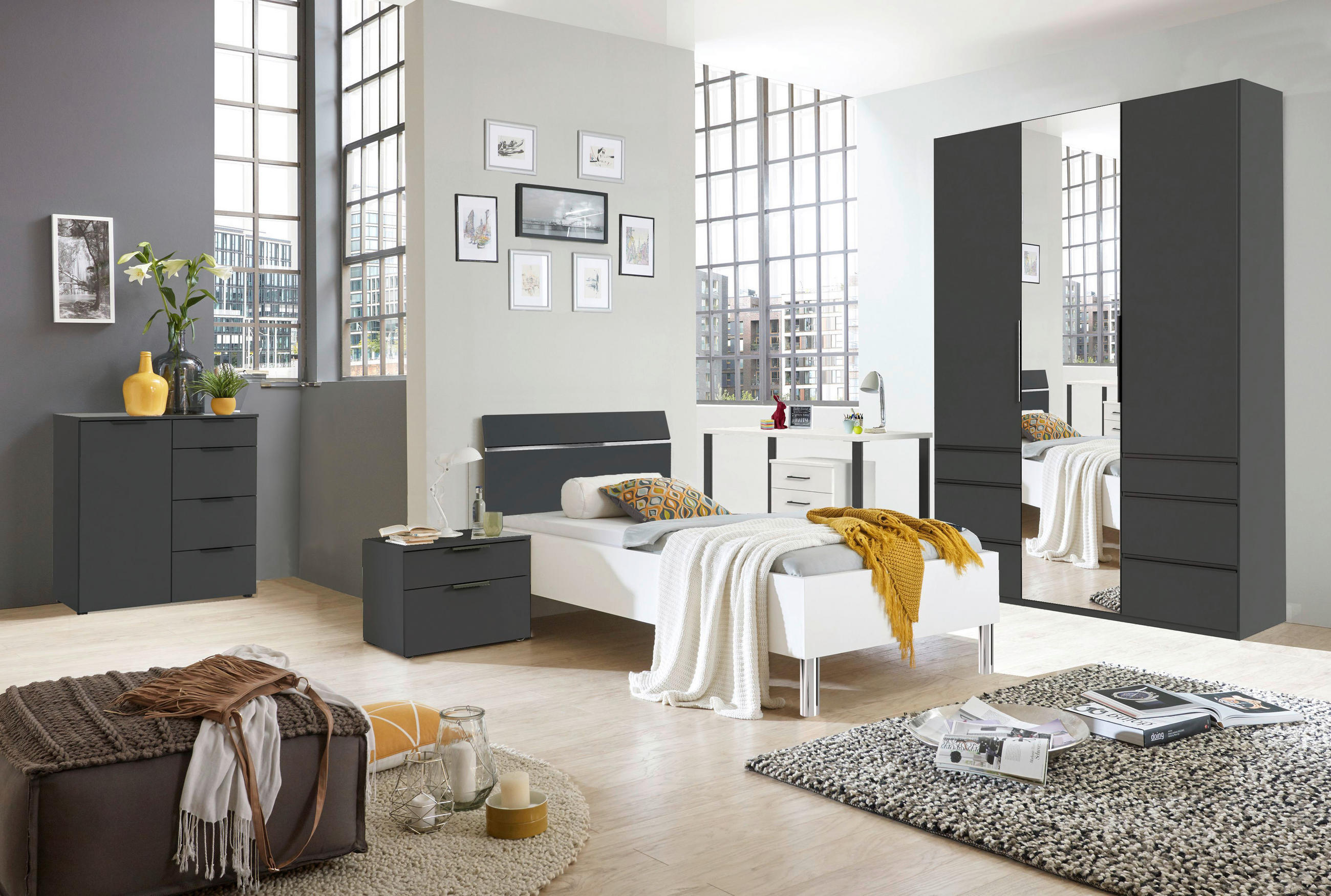 Minimalistična spalnica s posteljo, komodo in omaro, ki ustvarja mirno vzdušje.