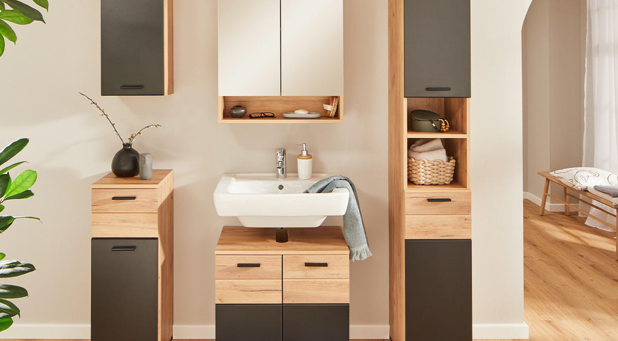 Modernes Badezimmer mit Holz-Badezimmermöbeln, einem Waschbecken, Spiegel und Stauraum. Dekoriert mit Pflanzen, Körben und stilvollen Accessoires für eine natürliche Atmosphäre