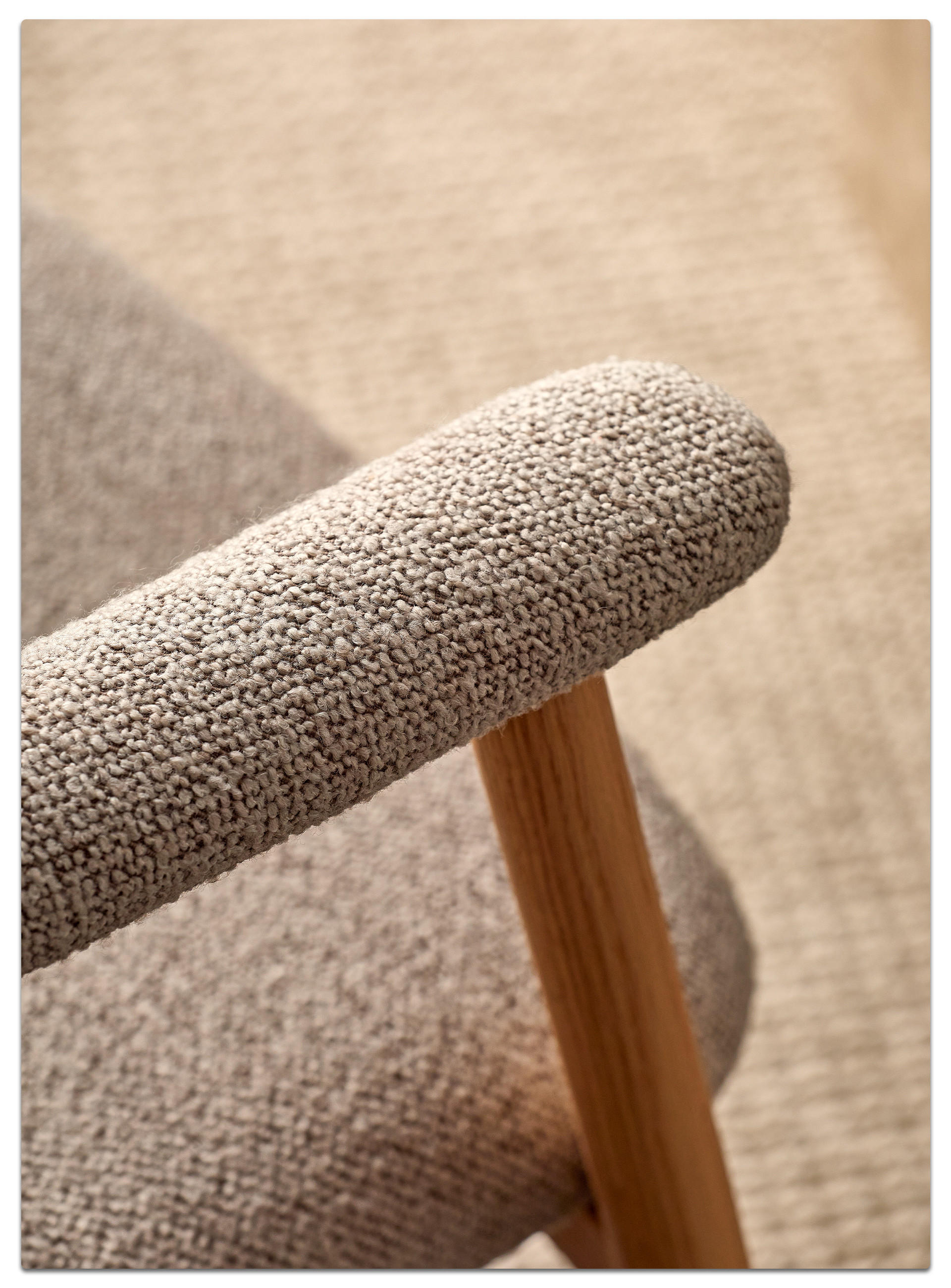 Nahaufnahme einer gepolsterten Armlehne in strukturiertem Stoff mit Holzgestell, passend zu einer gemütlichen Sitzmöbel‑Szene.