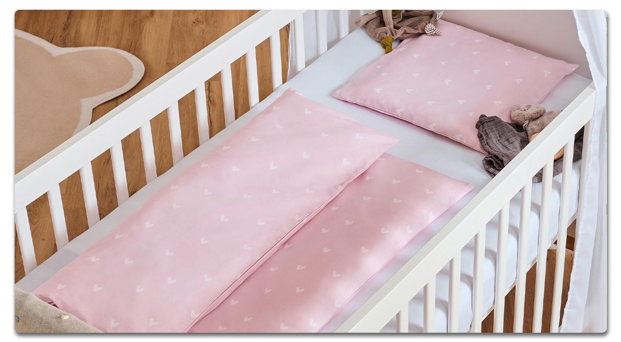 babygitterbett mit rosaner bettwäsche