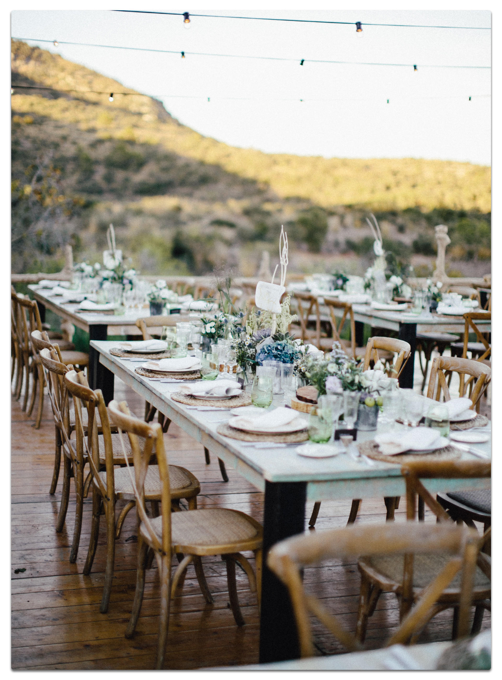 Hochzeitstisch mit Stühlen und Bergblick, dekoriert für eine Gartenhochzeit.