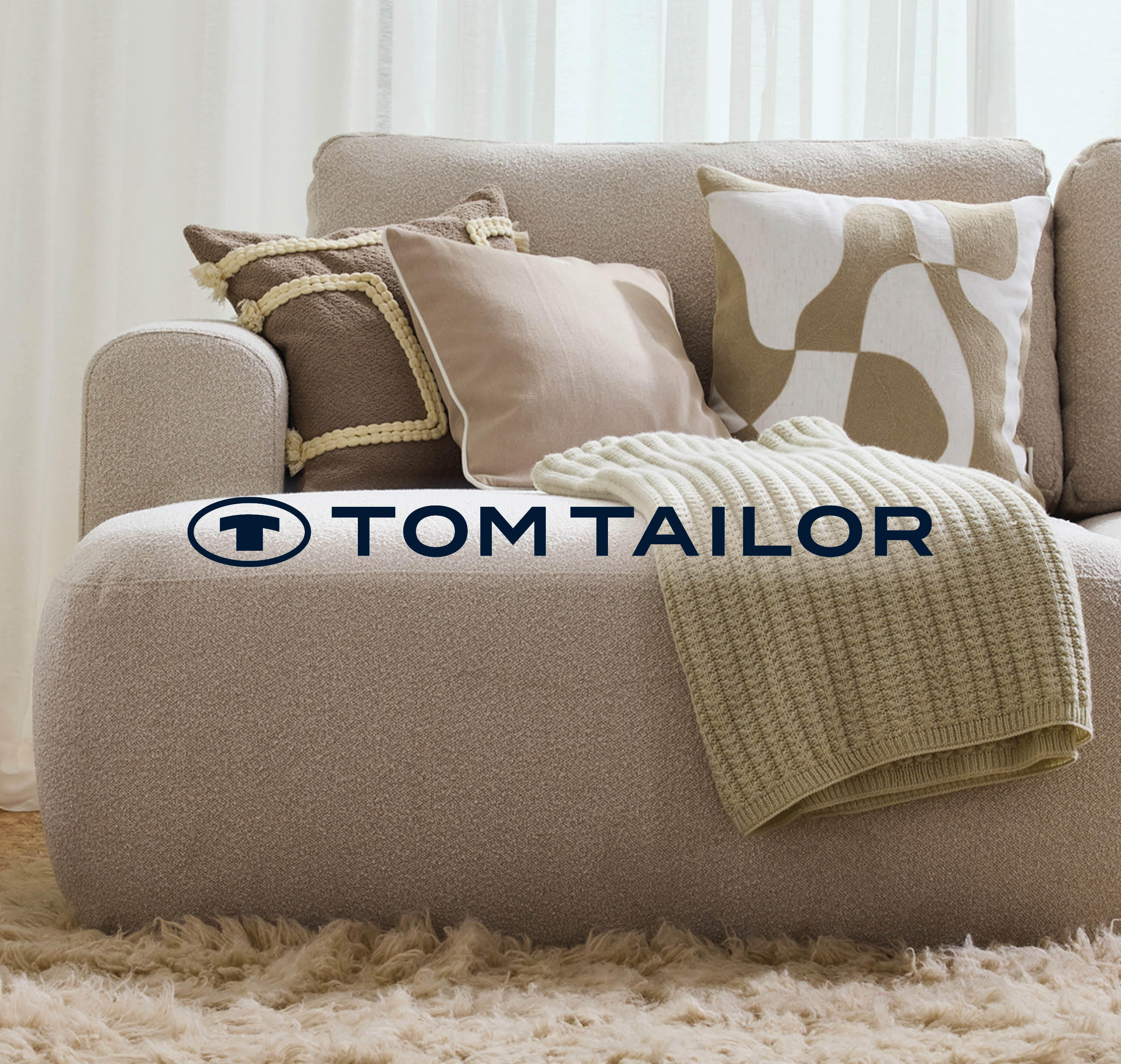 Wohnzimmer mit einer hell beigen Couch mit Kissen